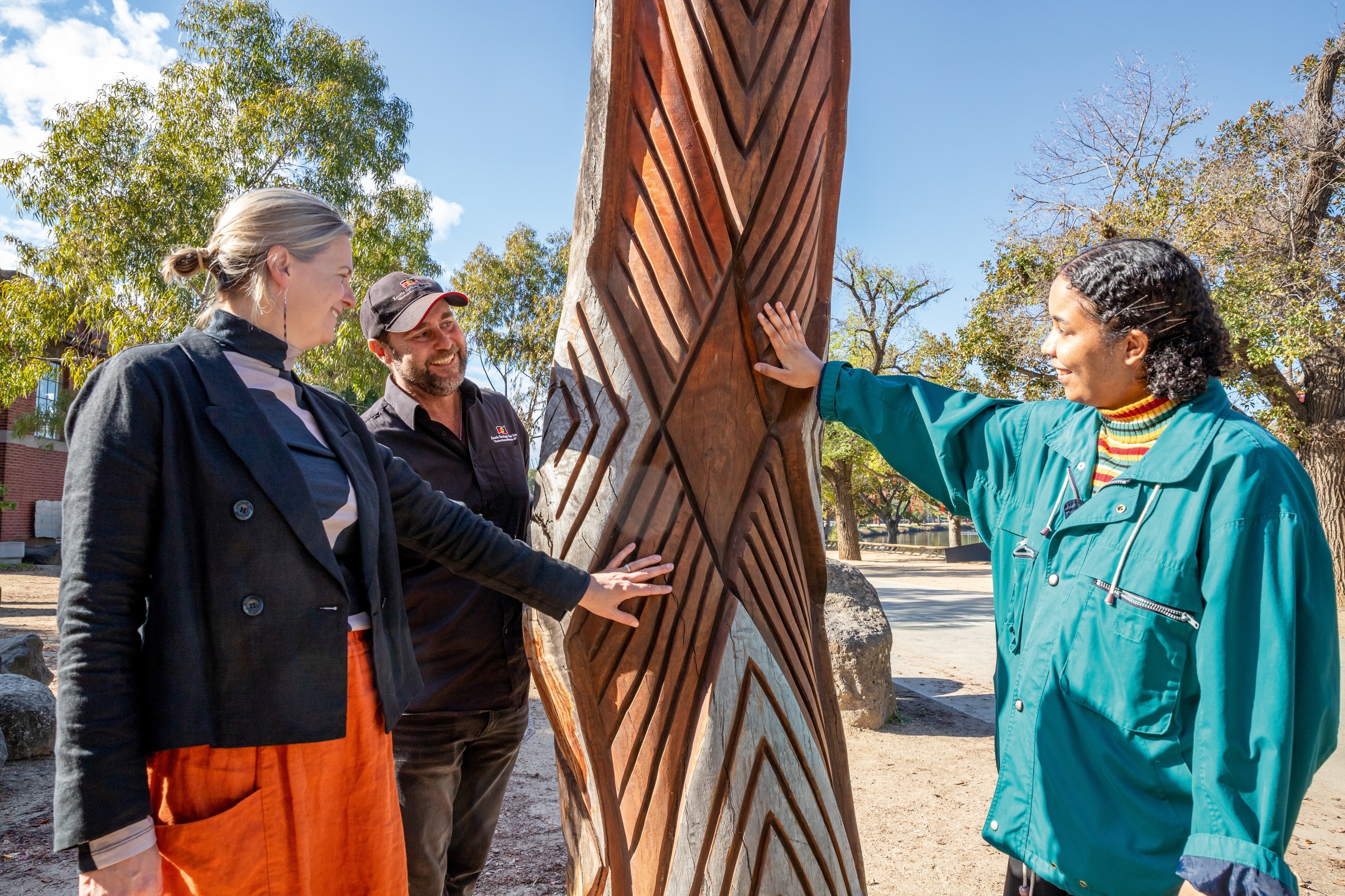 Three people holding up large piece of wood