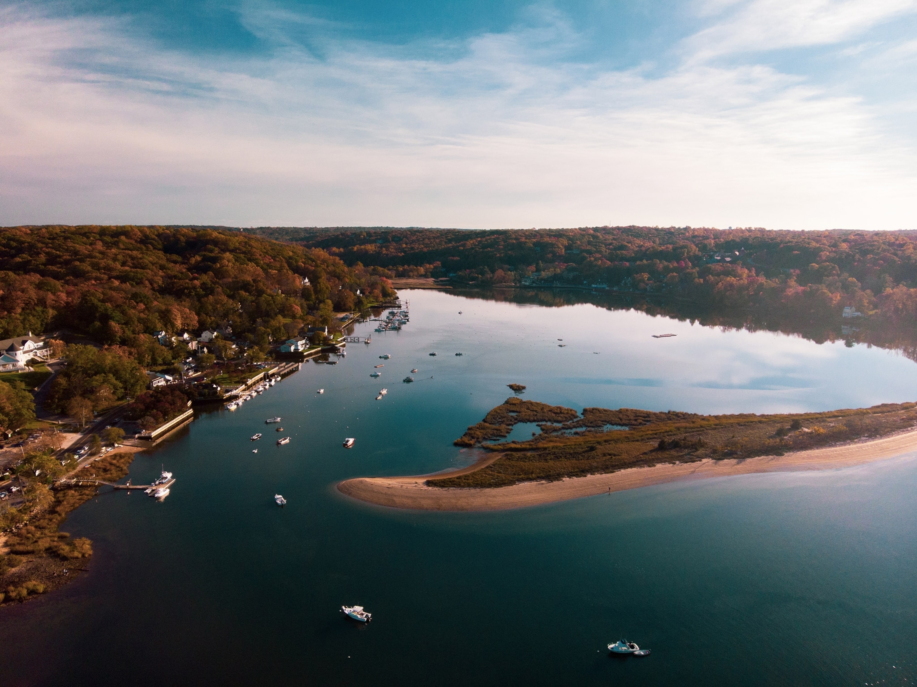 aerial photo of a harbor with boats and a long narrow peninsula jutting in from the right