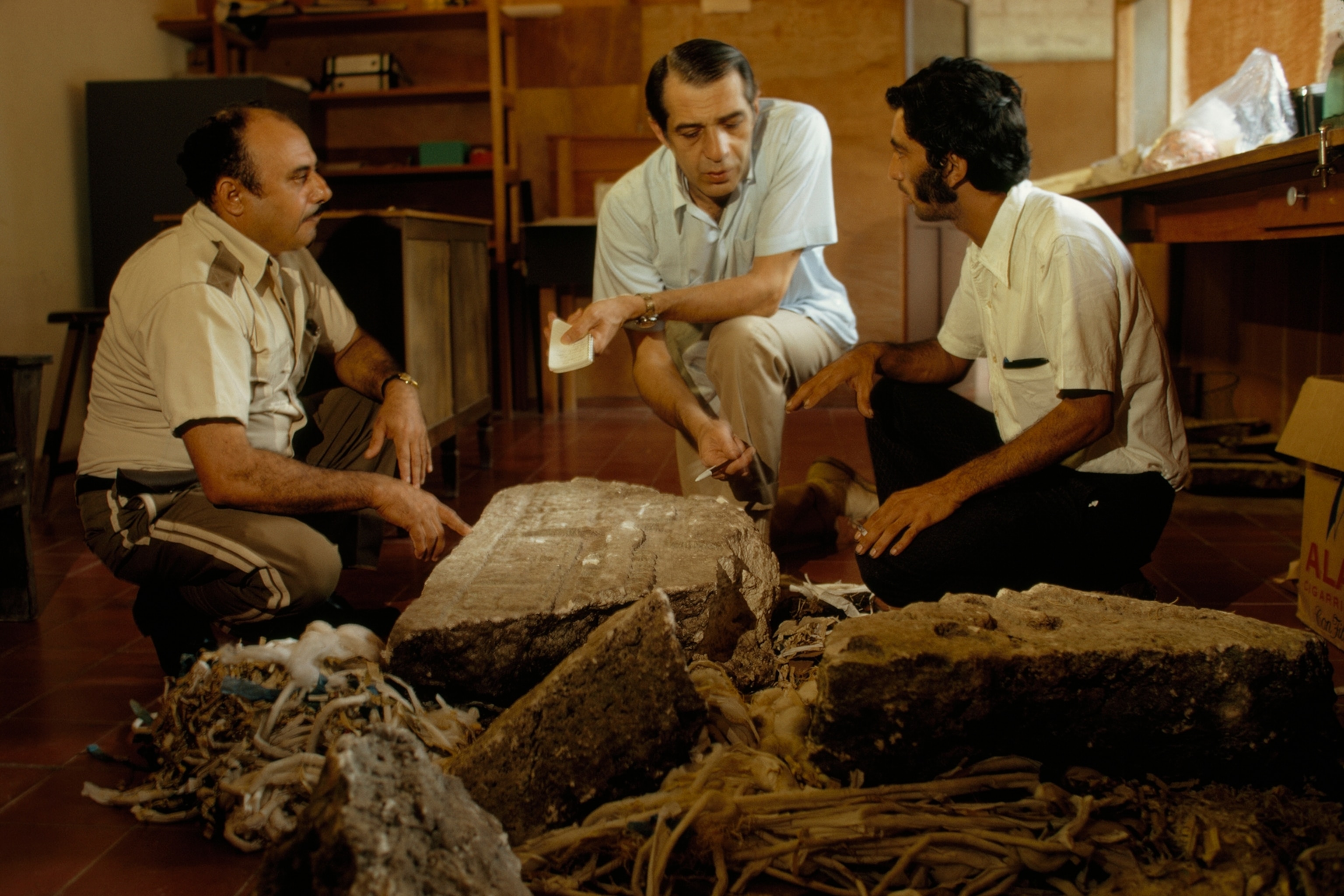 A shattered stela at Tikal (right) tells a sorry tale of loss to Washington, D. C., surgeon John Keshishian, center, who had admired it earlier at Agua teca, 70 miles to the southwest. Looters broke the heavy monu ment apart for easier transport and wrecked major glyphs. Police captured the men, but not before they had sold part of the loot. Miguel Orrego Corzo, Tikal National Park archeologist, right, and a guard discuss the impossible task of trying to safeguard countless Middle American sites.