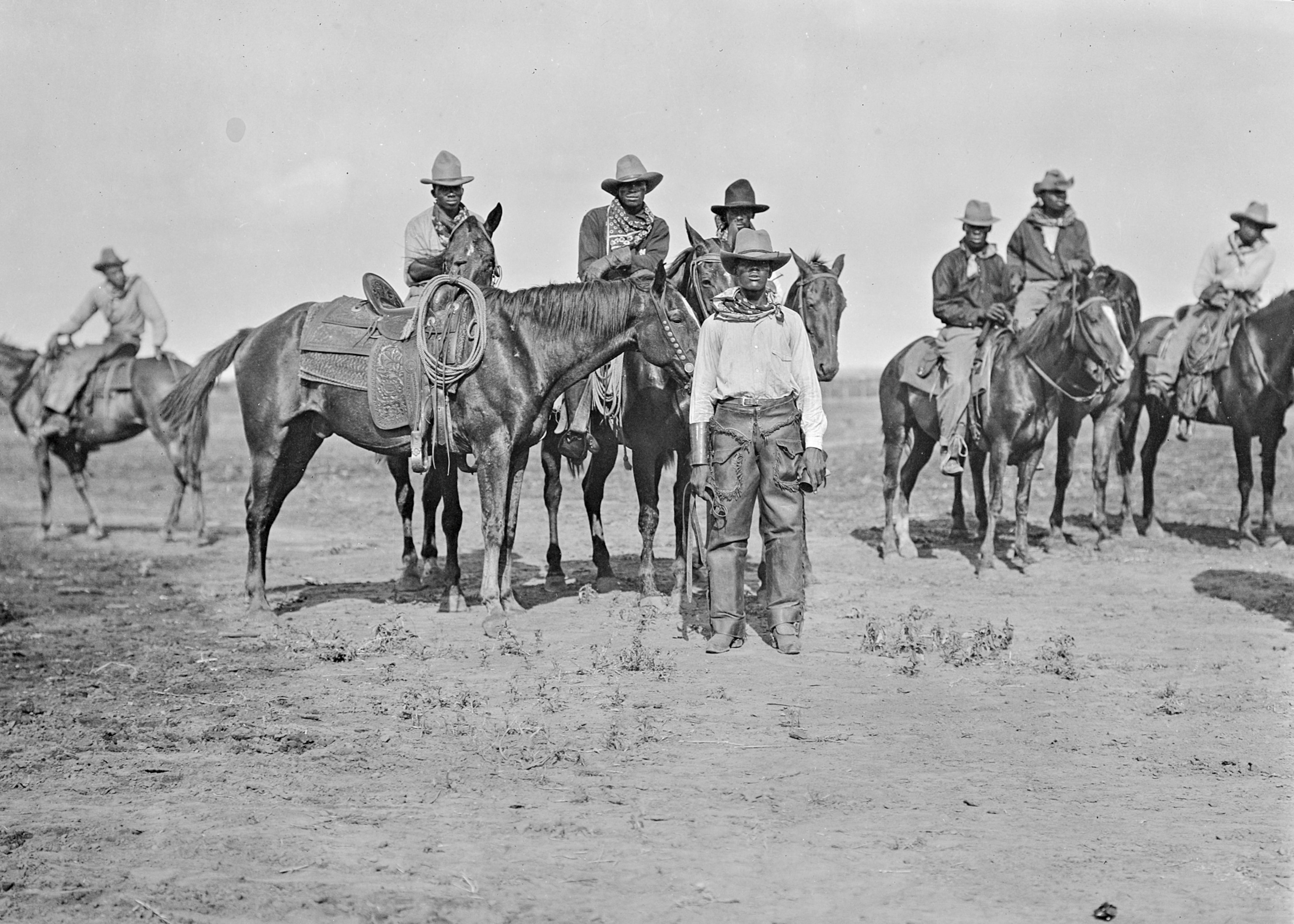 A group of people some on horses on a black and white background.