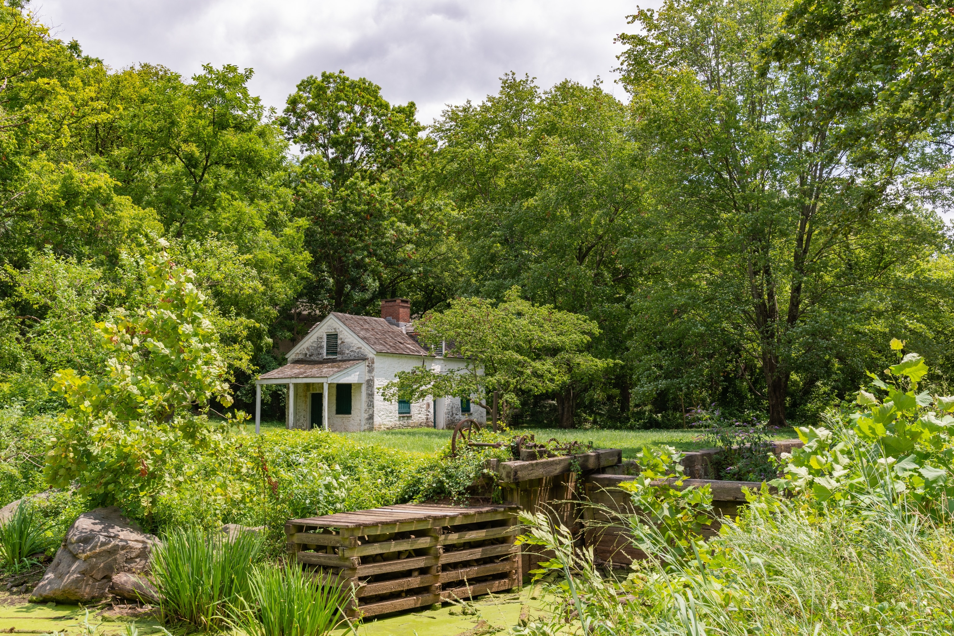 An old white lockhouse sits tucked away in the trees.