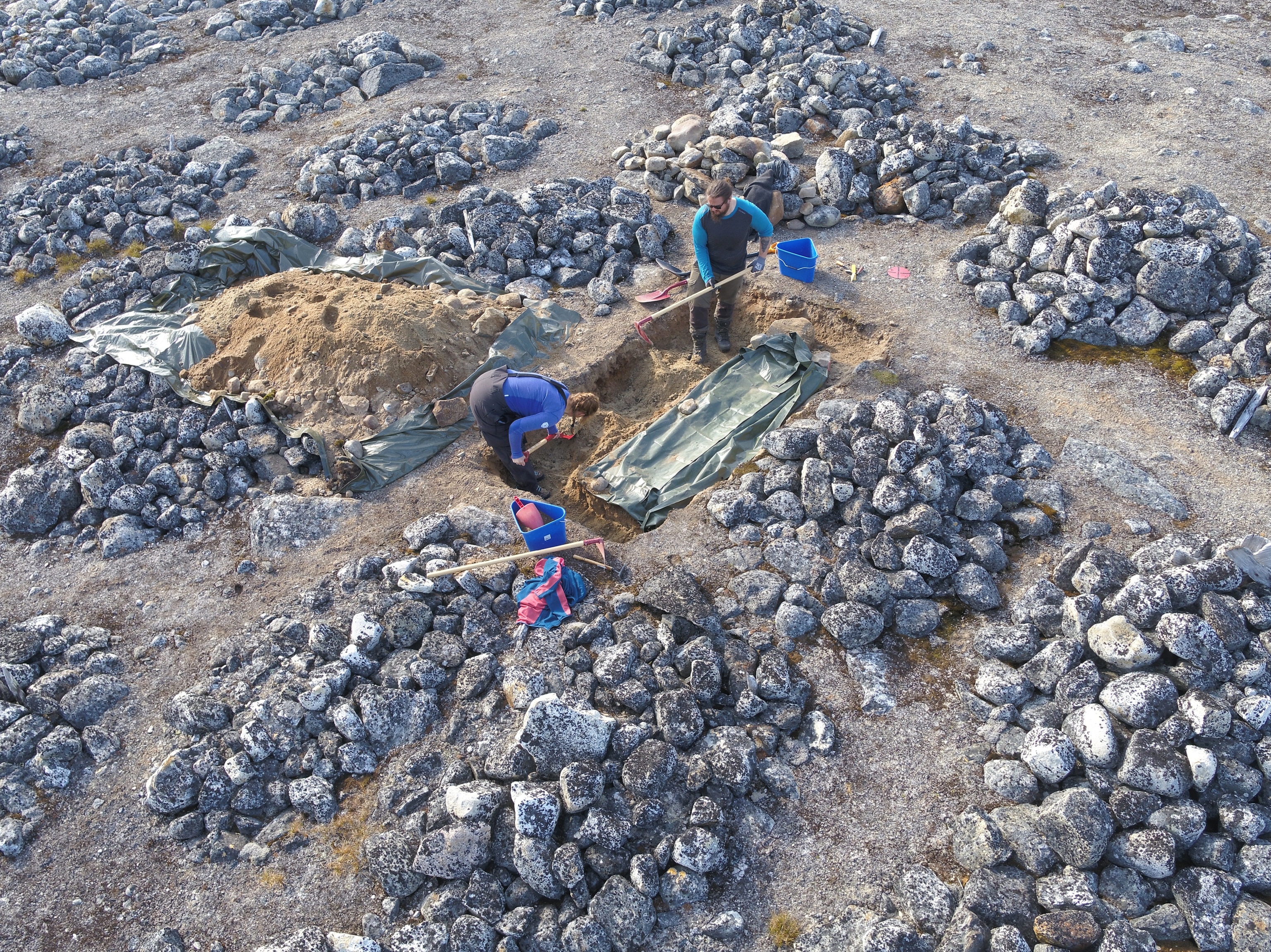 two people dig amongst piles of large round stones