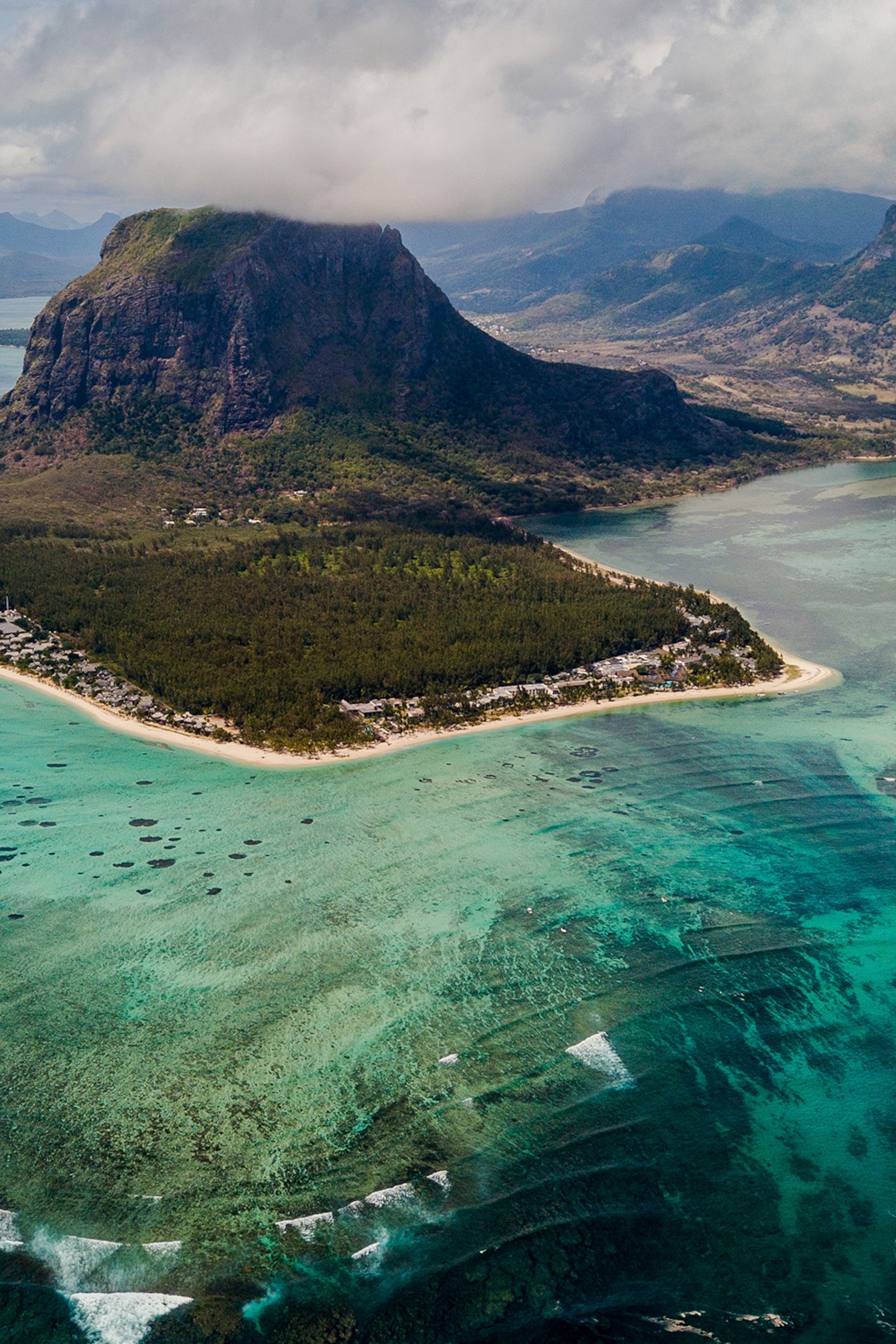 An aerial view of an island and crystal-blue ocean.