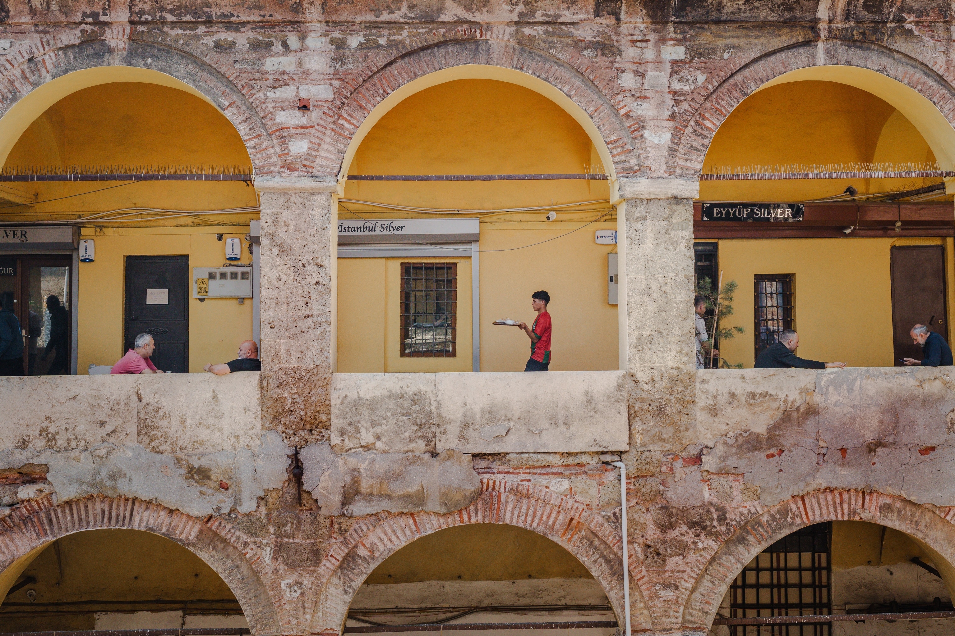 A young boy carries a tray of tea through an ancient building.