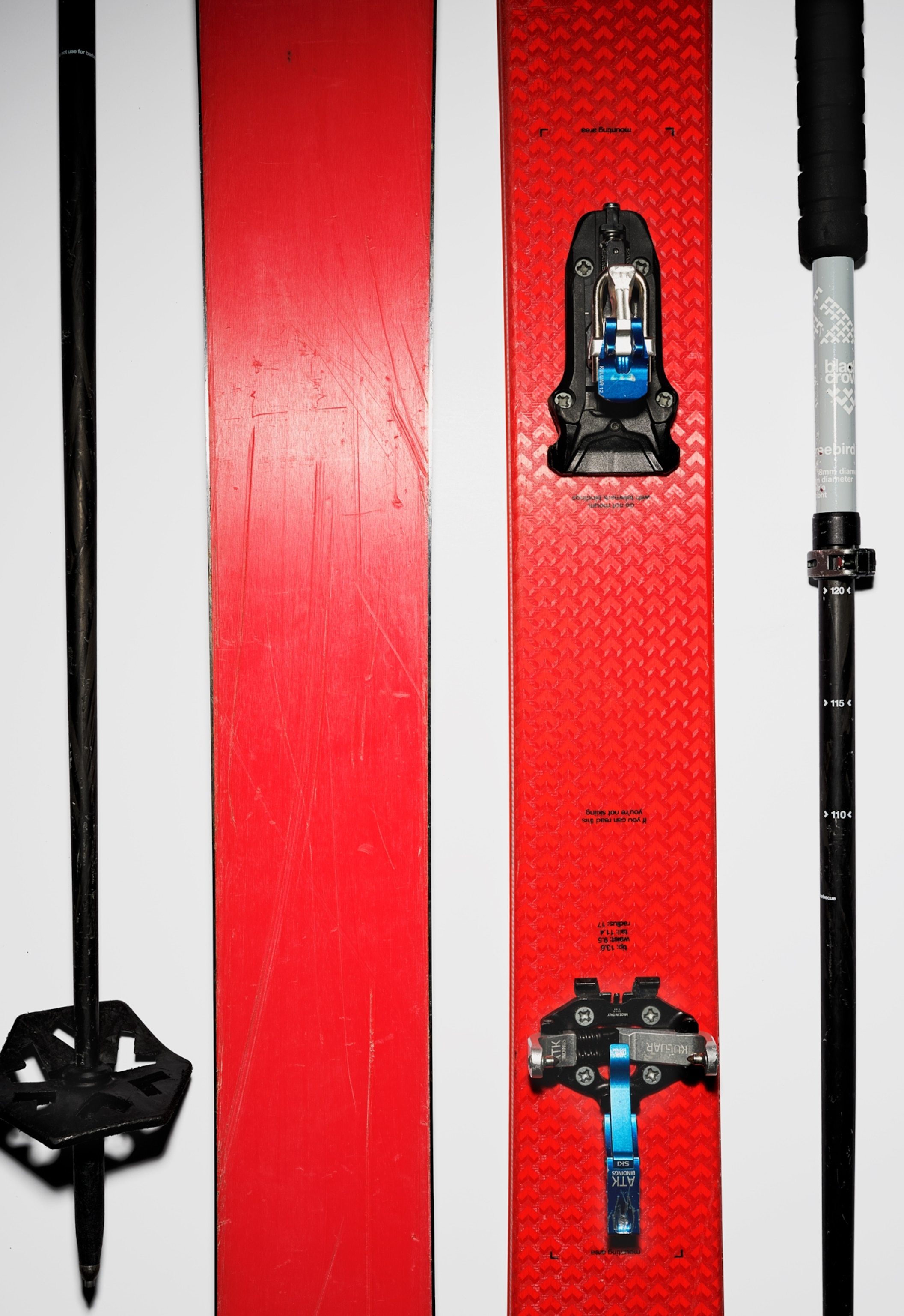 A pair of red skis lies on a white background