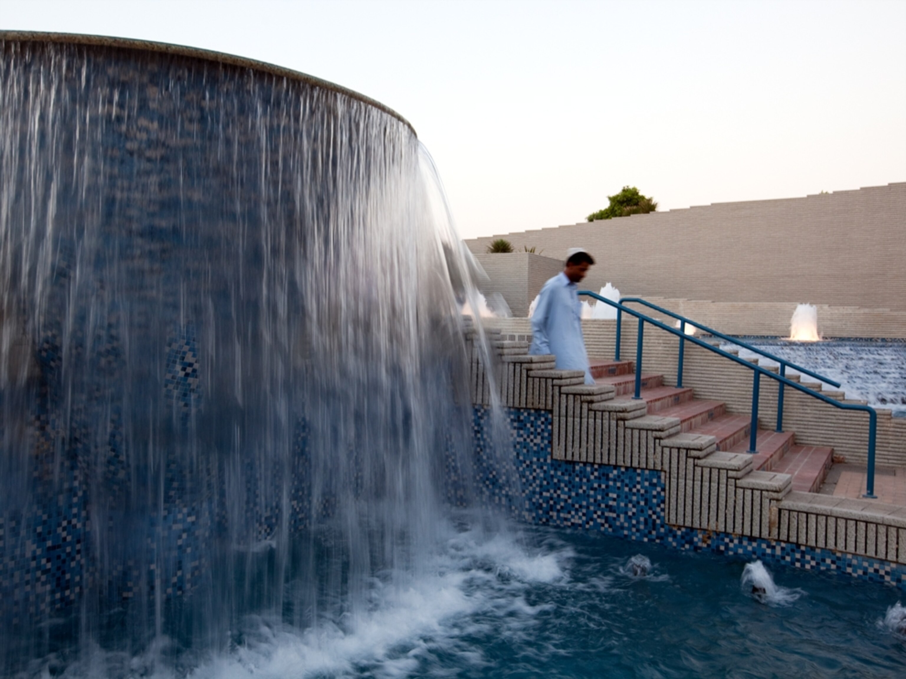 Man walking past a fountain (photo)