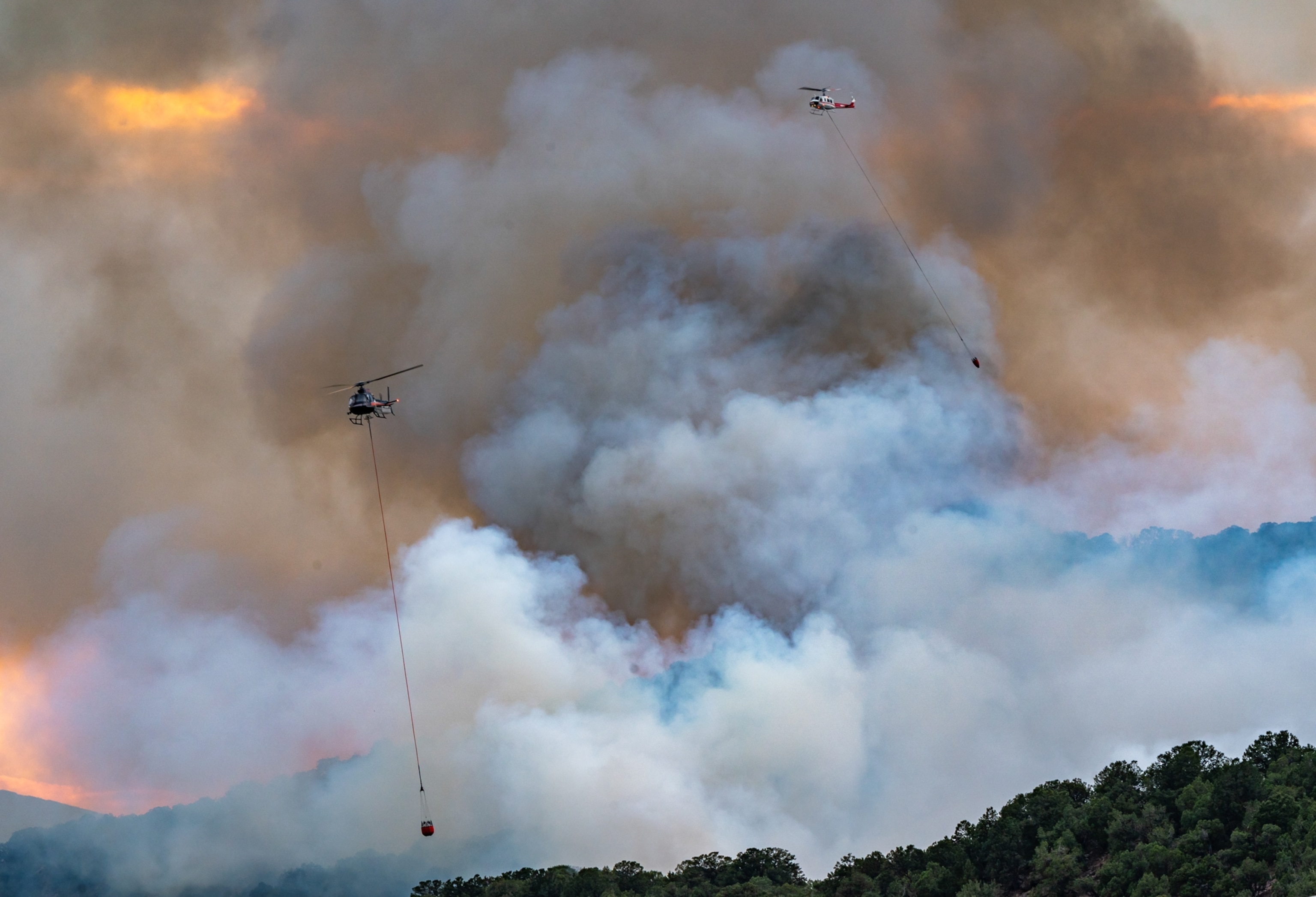 Fire fighting helicopters fly over Basalt, CO during the Lake Christine Fire.