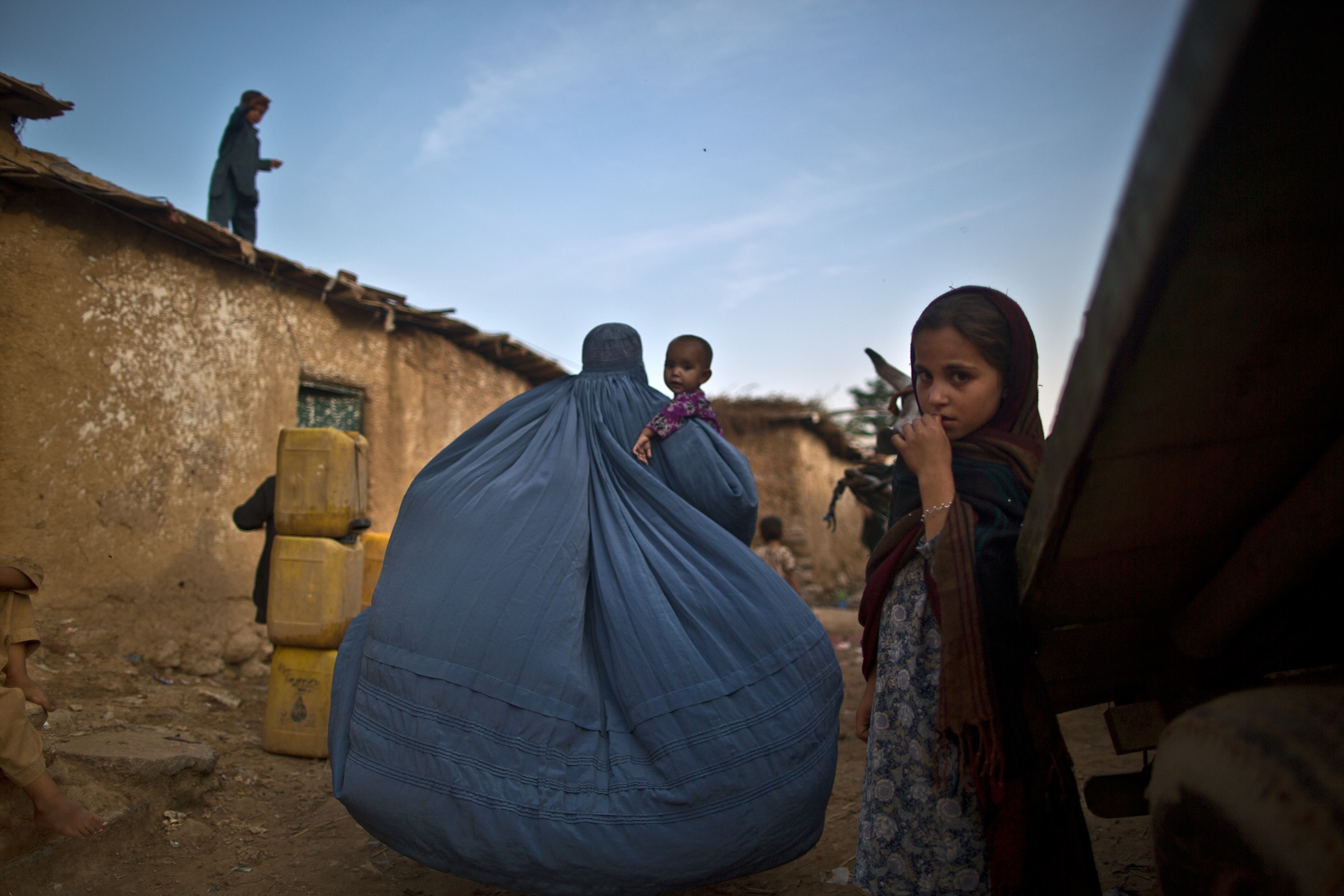 Pictures We Love - Picture of an Afghan refugee in Pakistan walking home through an alley as her burka billows out behind her