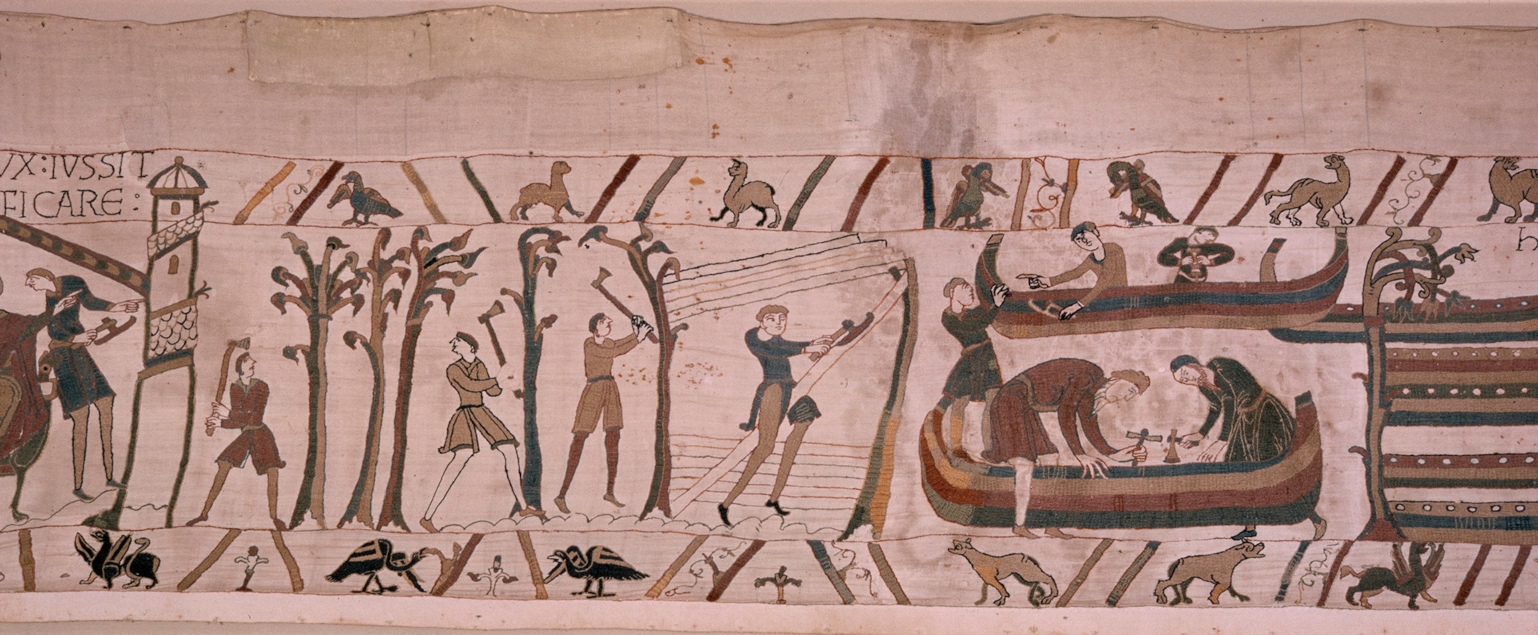 A scene from the tapestry in which men fell trees and build a ship.