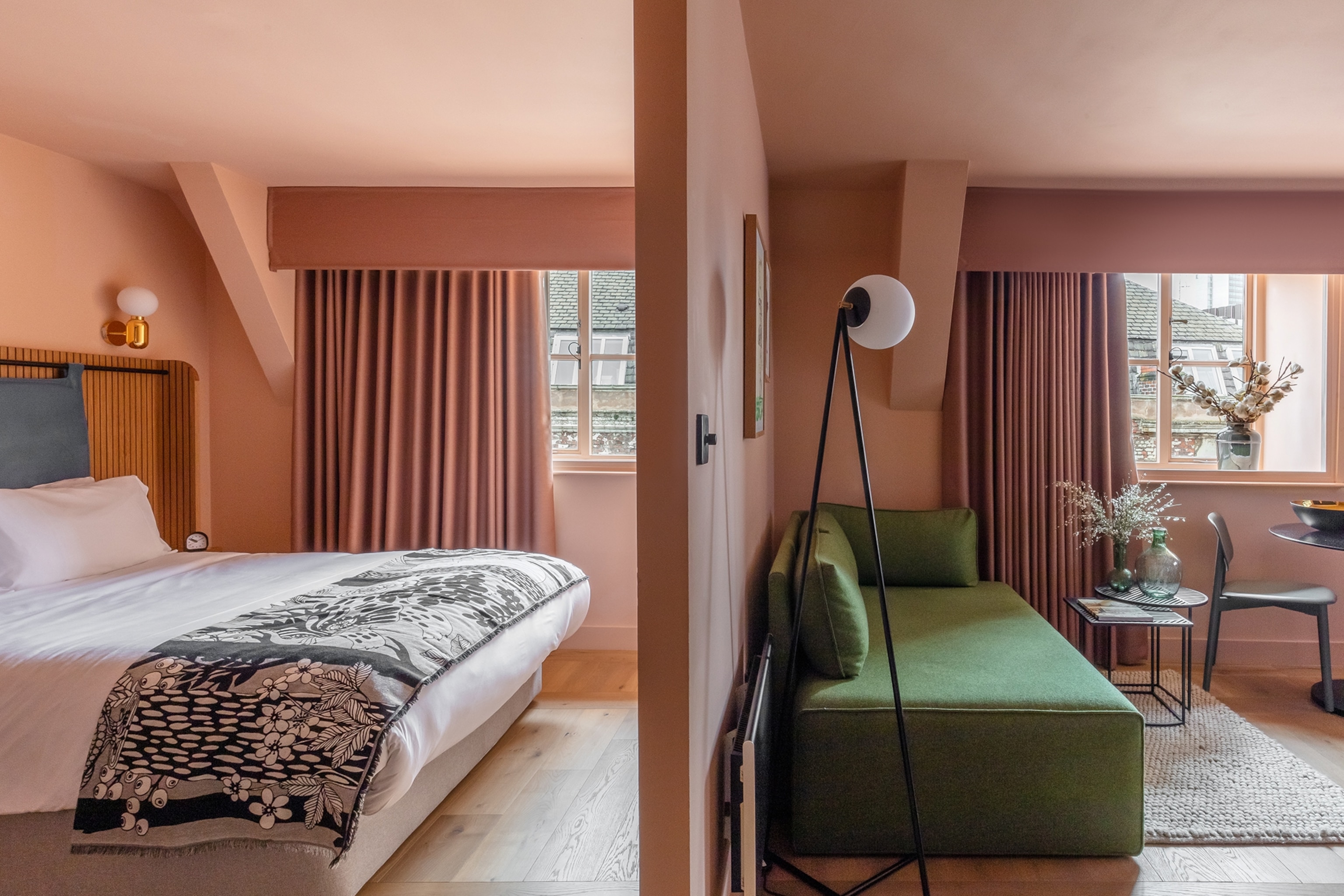 A landscape view into a hotel bedroom with one side featuring a double bed and the other side a living room area.