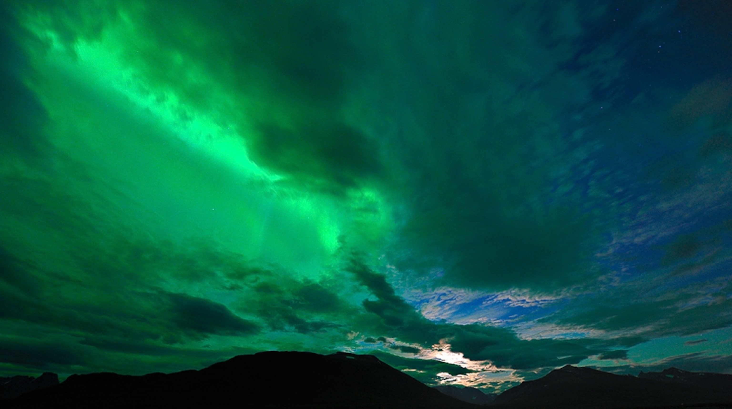 an aurora behind clouds over Norway