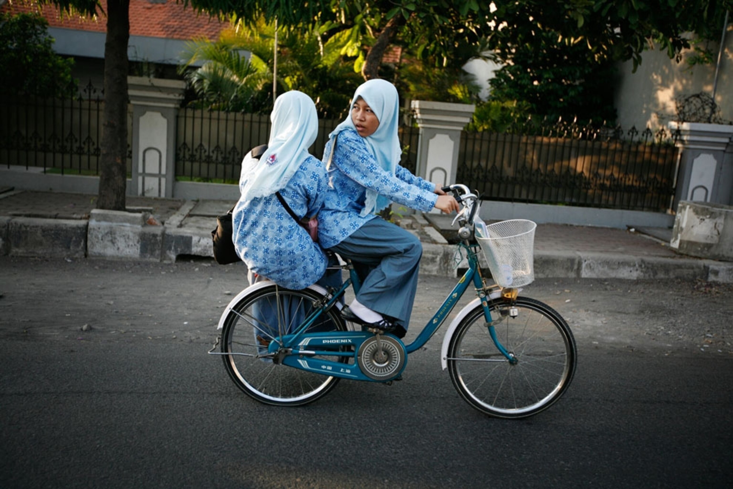 Two girls riding a bike on the way to school in Surabaya, Indonesia