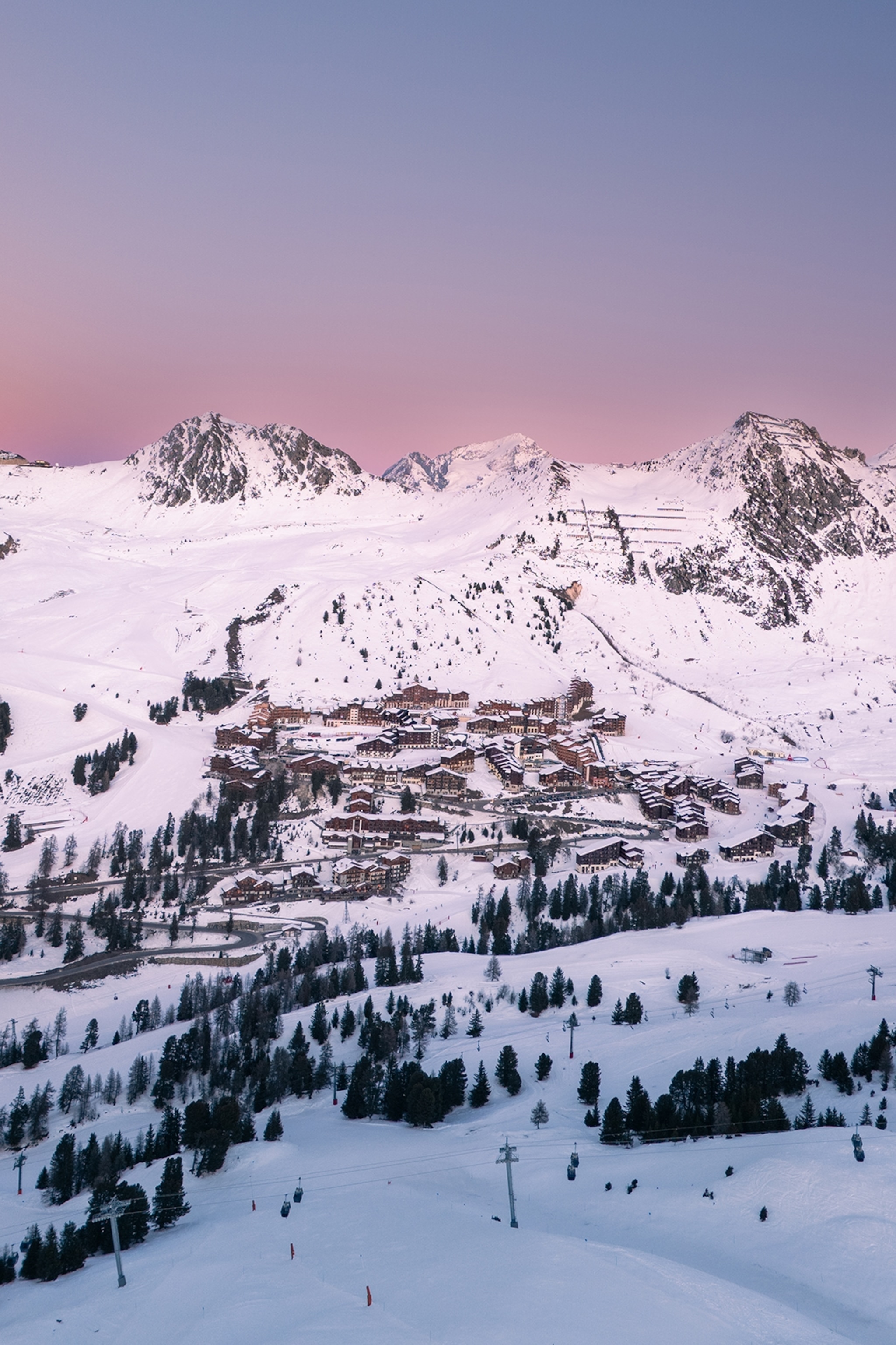 A picturesque village in a snowy mountain valley at early dawn.