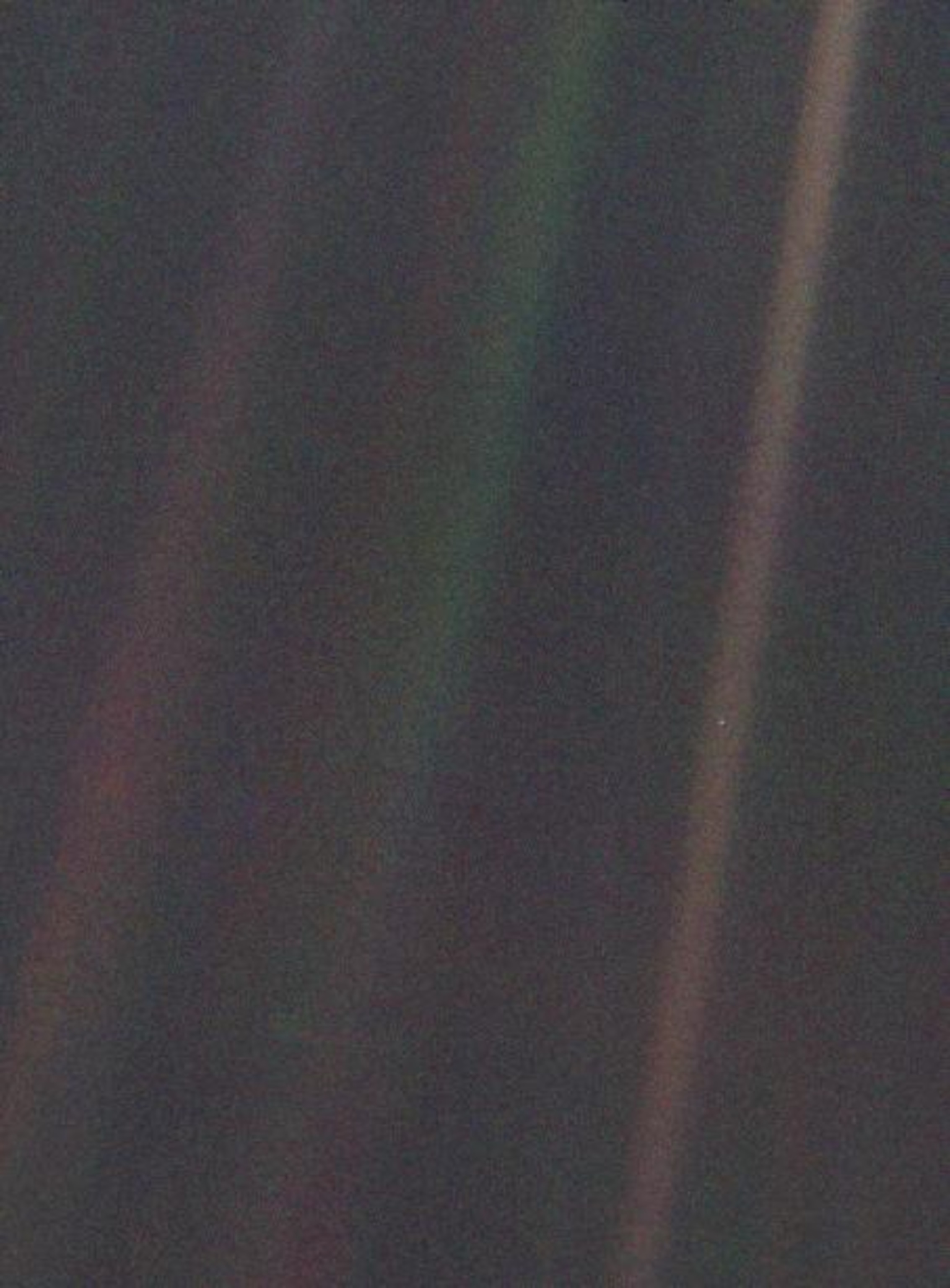 Faded bands of colored light, with a tiny pale dot falling within one of the colorful bands