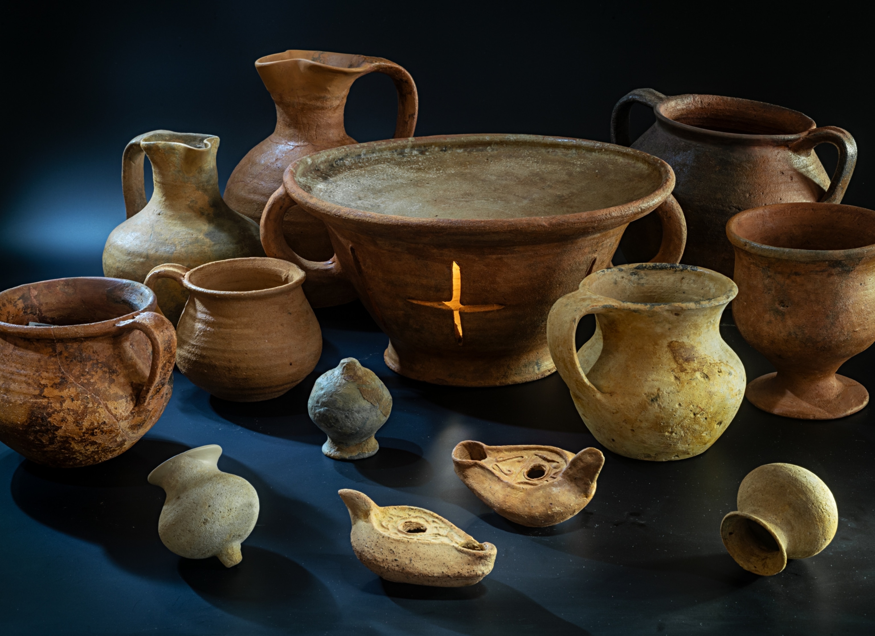 Thirteen different ceramic artifacts of varying sizes and colors.