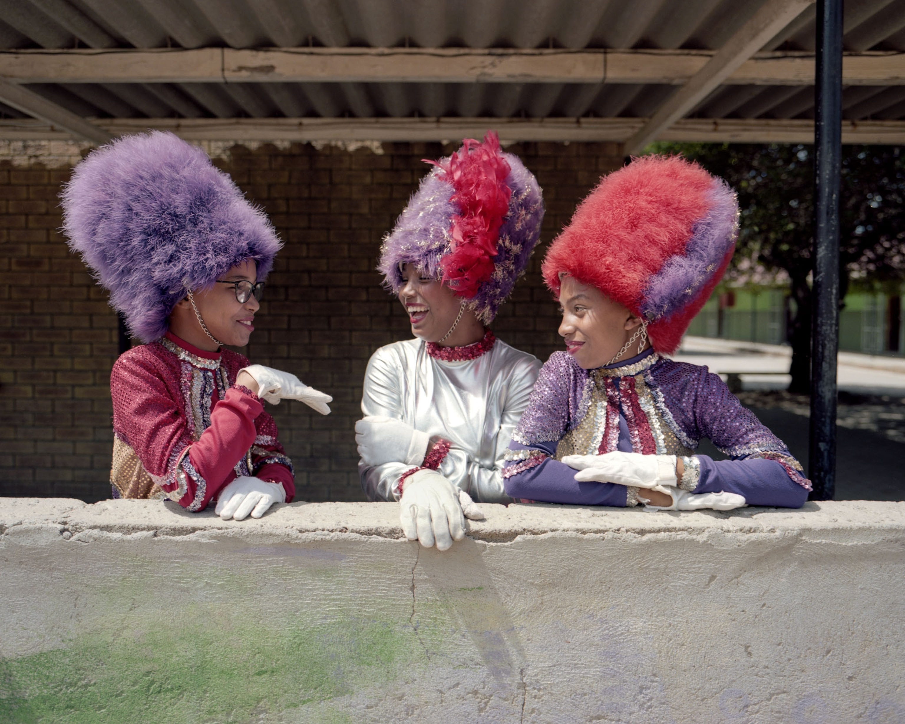 three young women in large fuzzy hats talking
