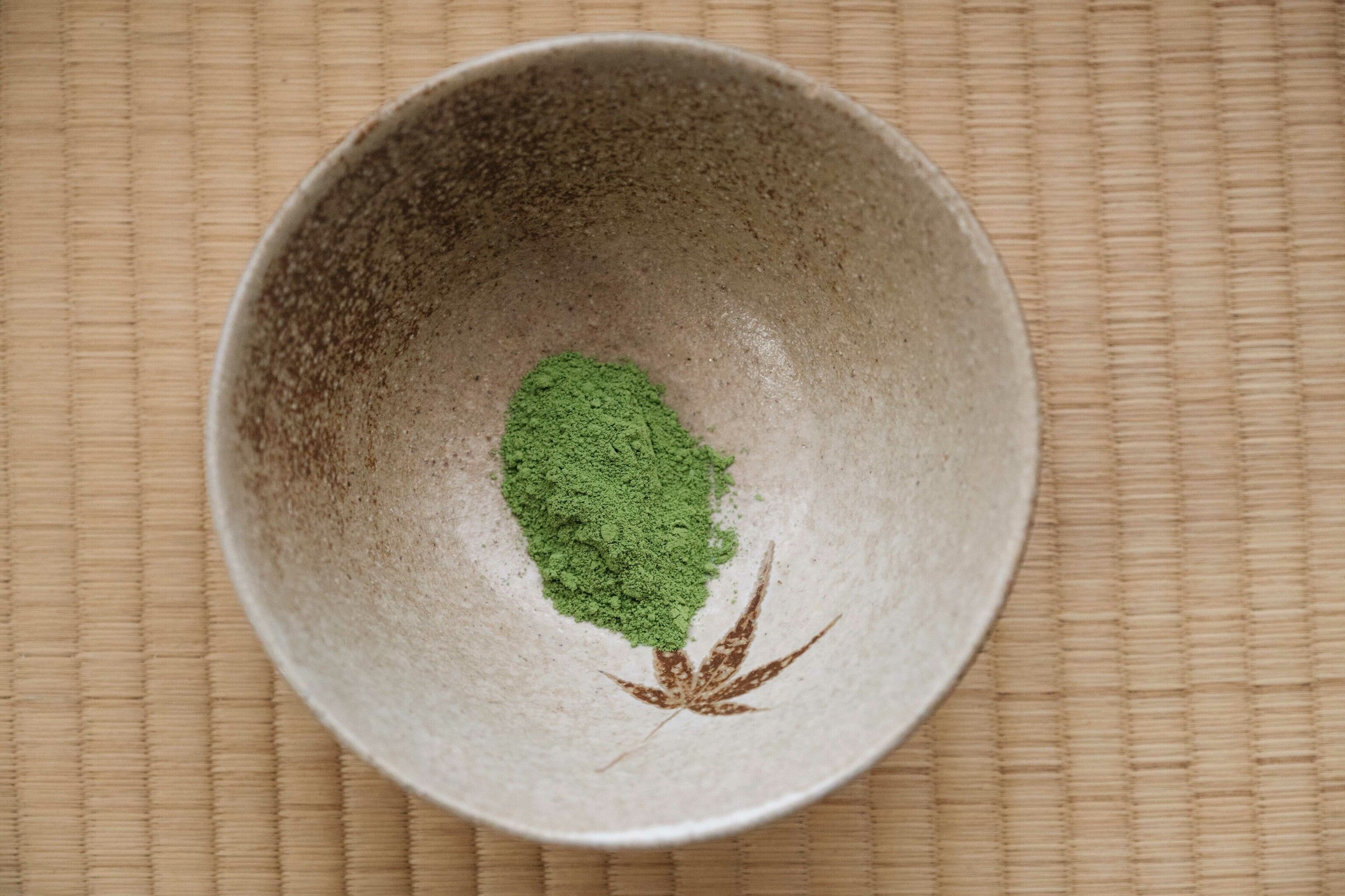 Ground green tea leaves in a white bowl.
