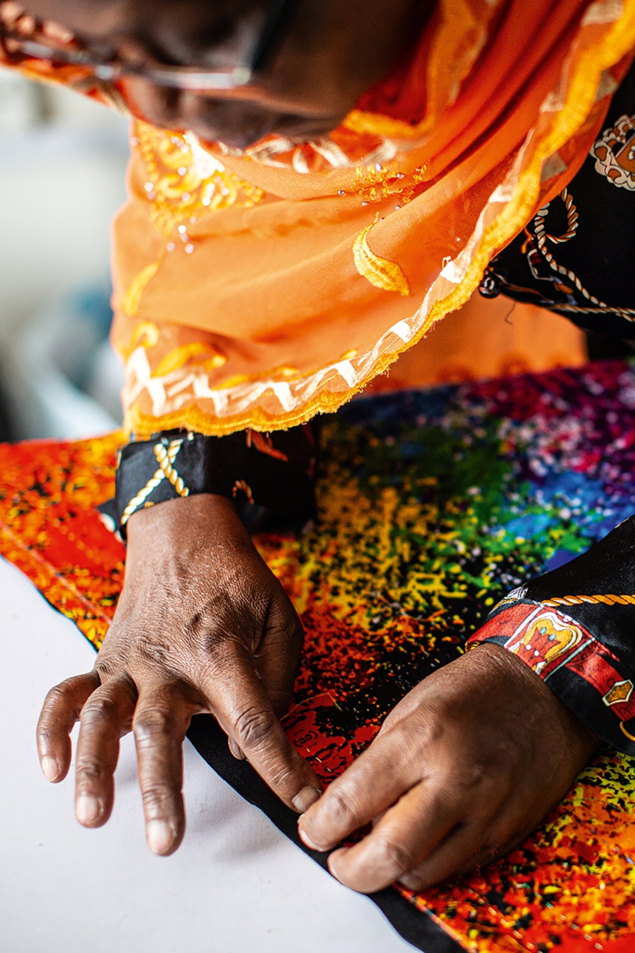 A female artisan from Rwanda working closely on a neck scarf.