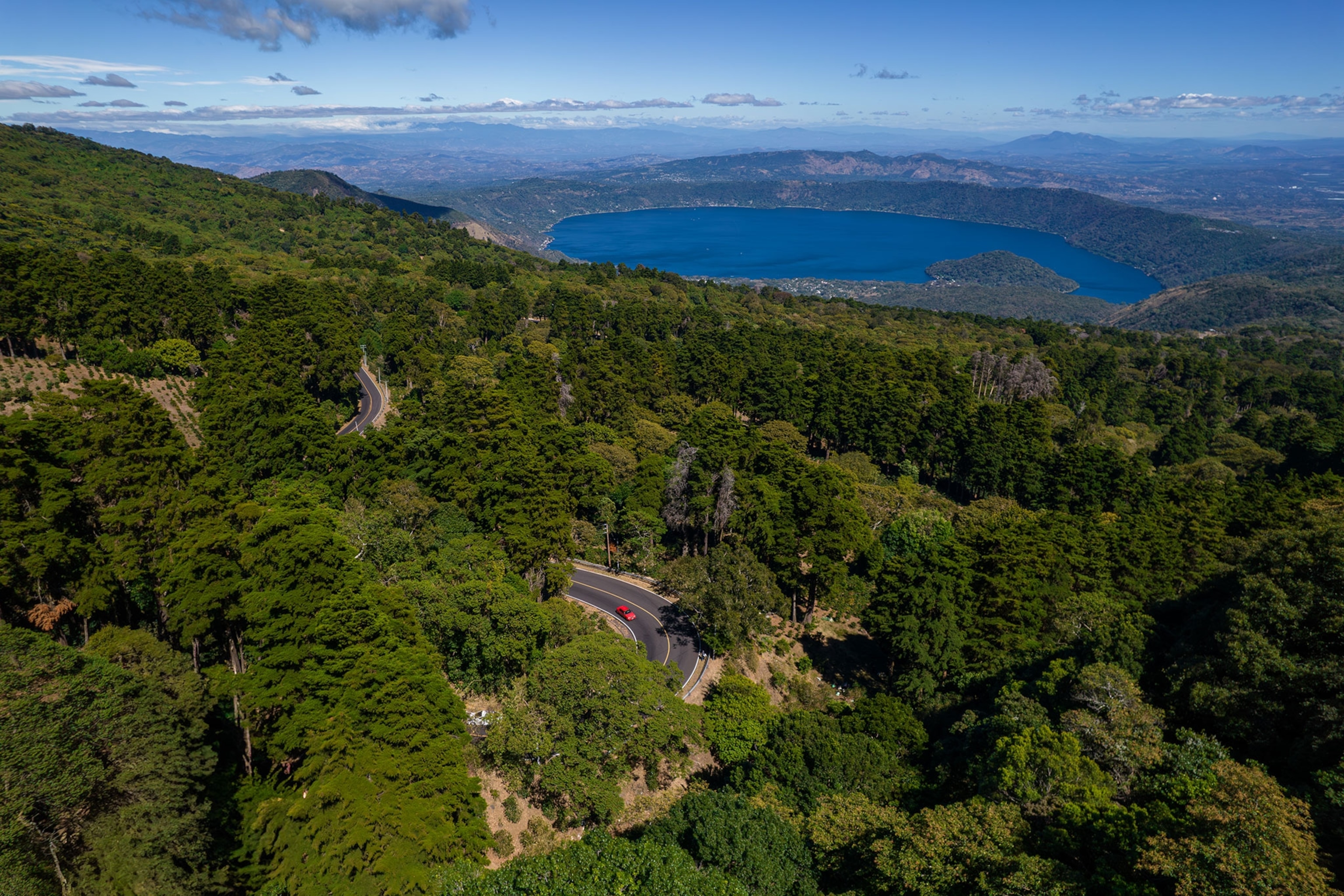 A green forest with a blue Lake Coatepeque in the background, El Salvador.