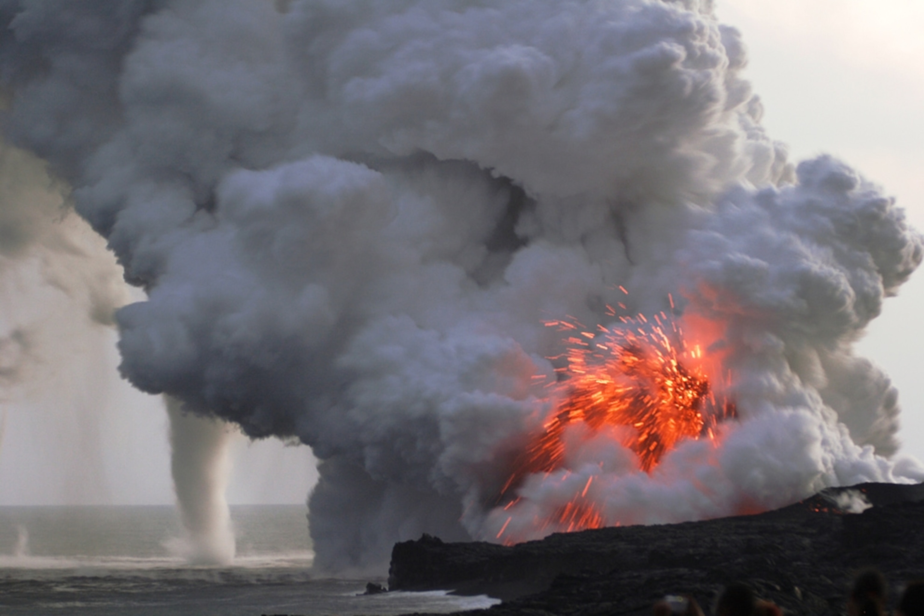 a waterspout next to an erupting volcano in Hawaii