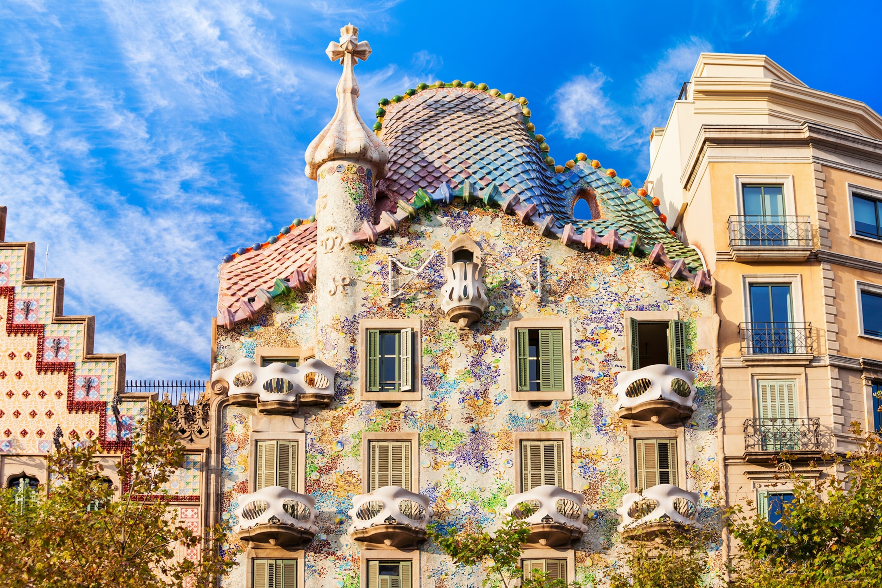 A light tan building with a curved roof and balconies shaped like whimsical faces.