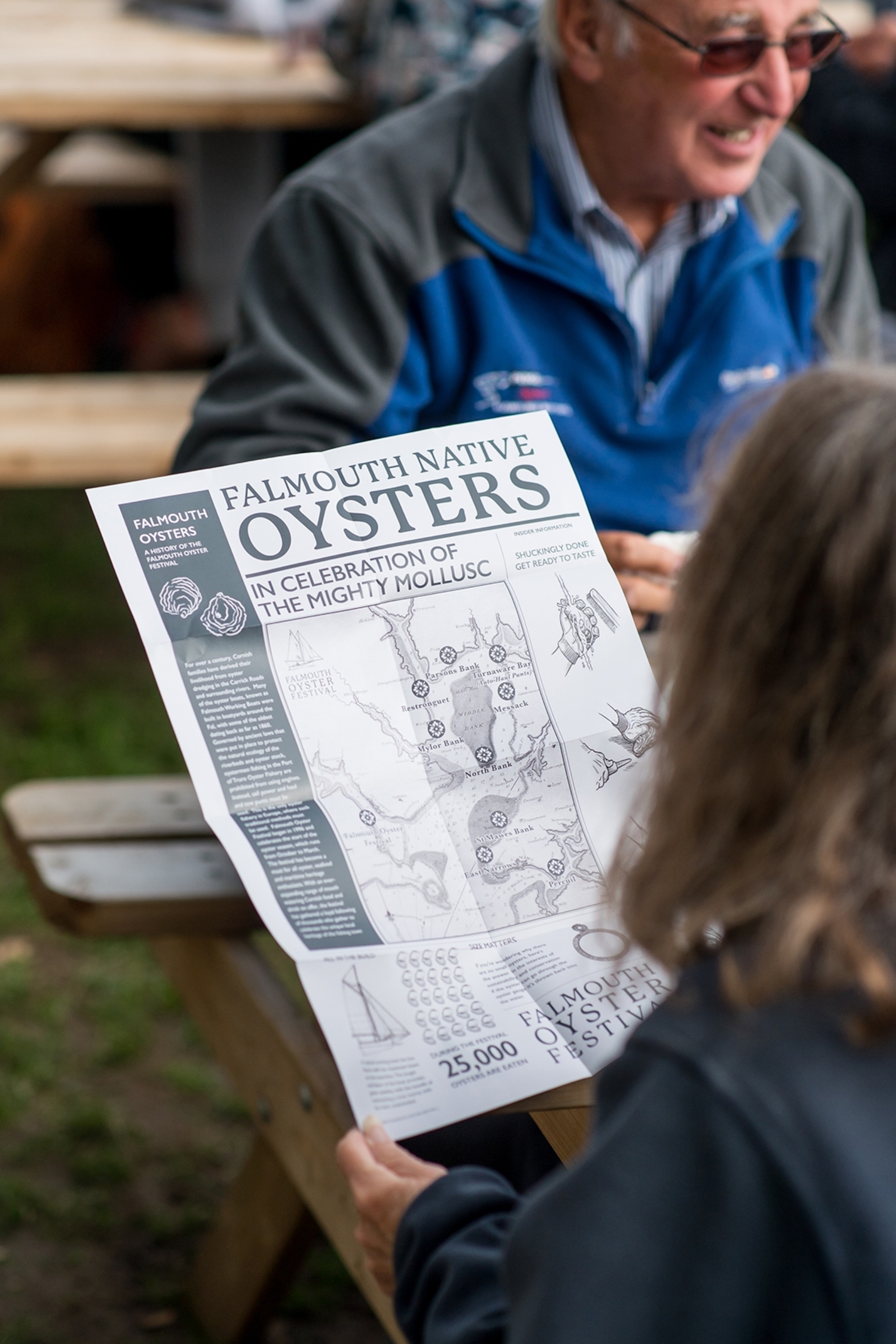 An oyster festival brochure held up by a visitor and shot from behind the shoulder.