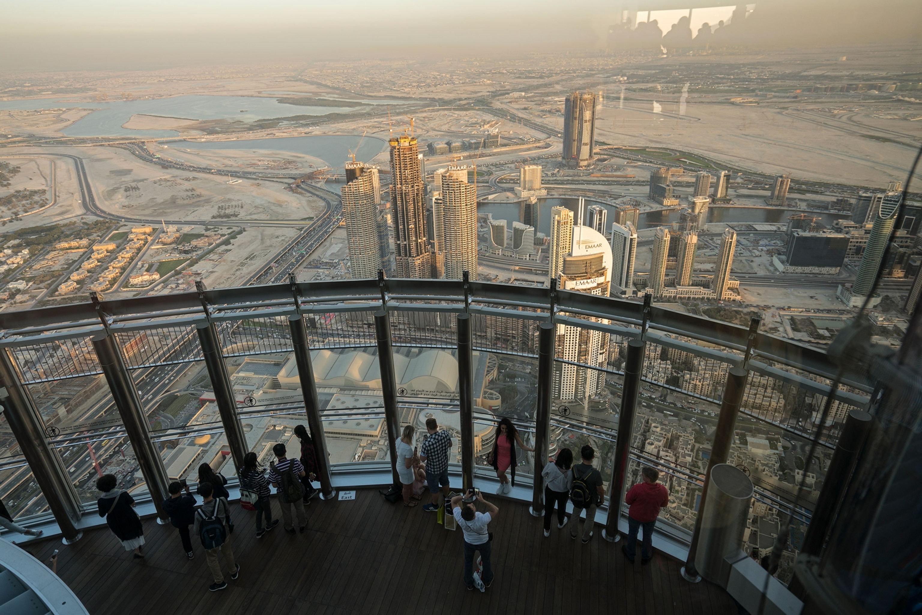 visitors peering over Dubai from an observation deck at the Burj Khalifa in UAE