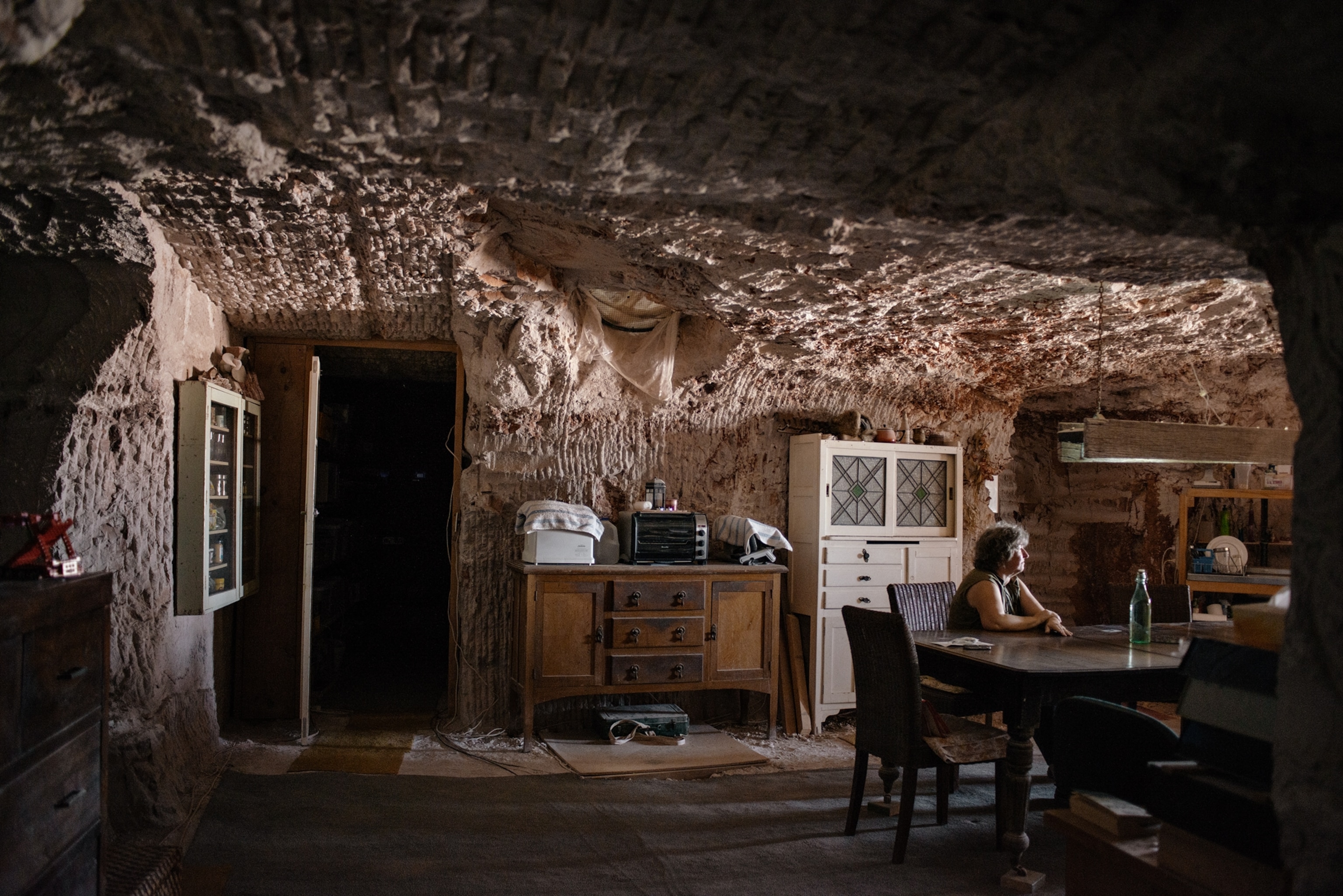 A woman sits at a table in her kitchen underground.