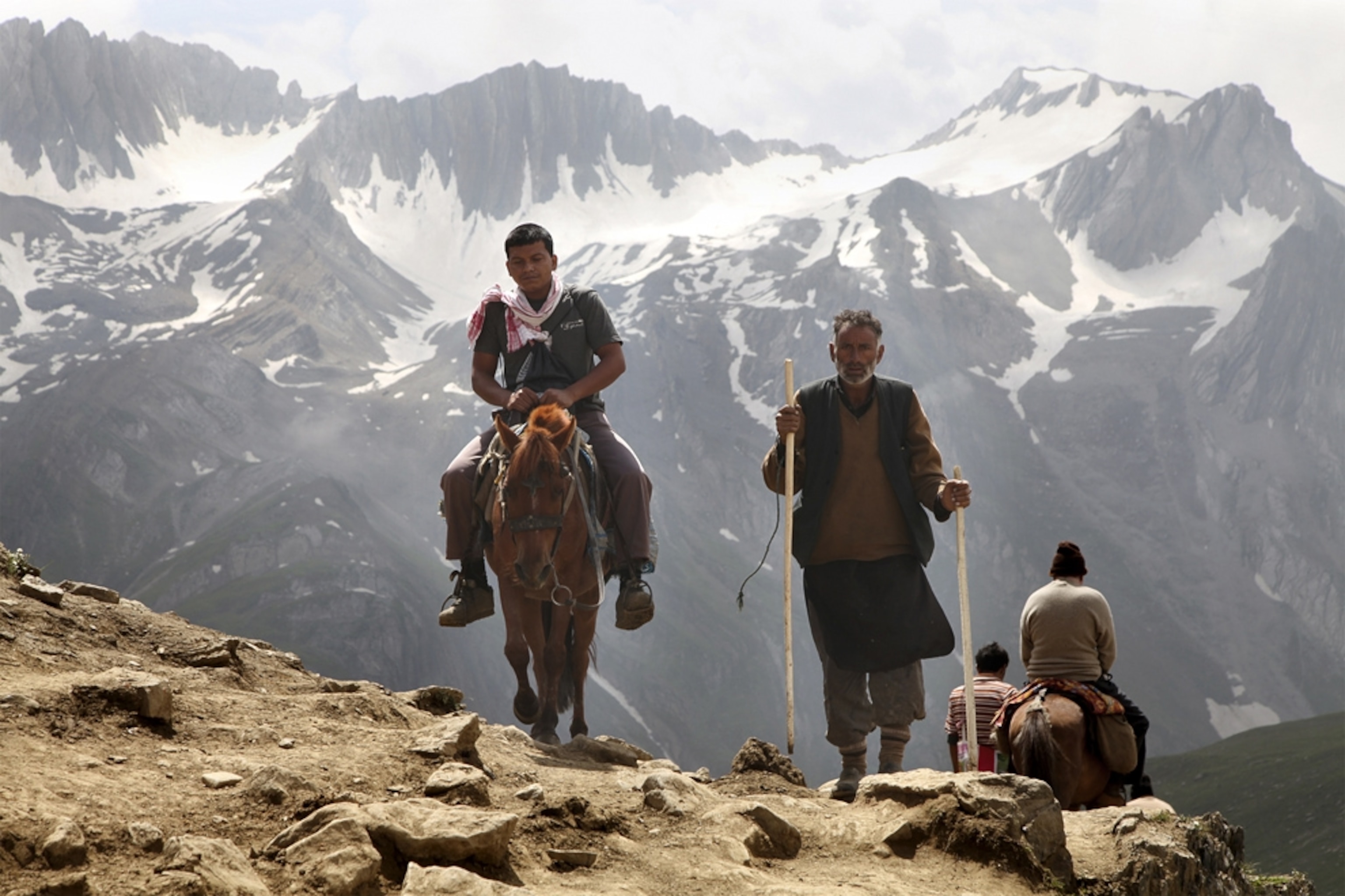 On foot and on horseback, Hindu pilgrims walk over Mahagunas Pass during the Amarnath Yatra pilgrimage route.