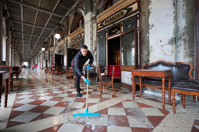 A man brushes away floodwater outside the historic Caffe Florian, in San Marco Square.