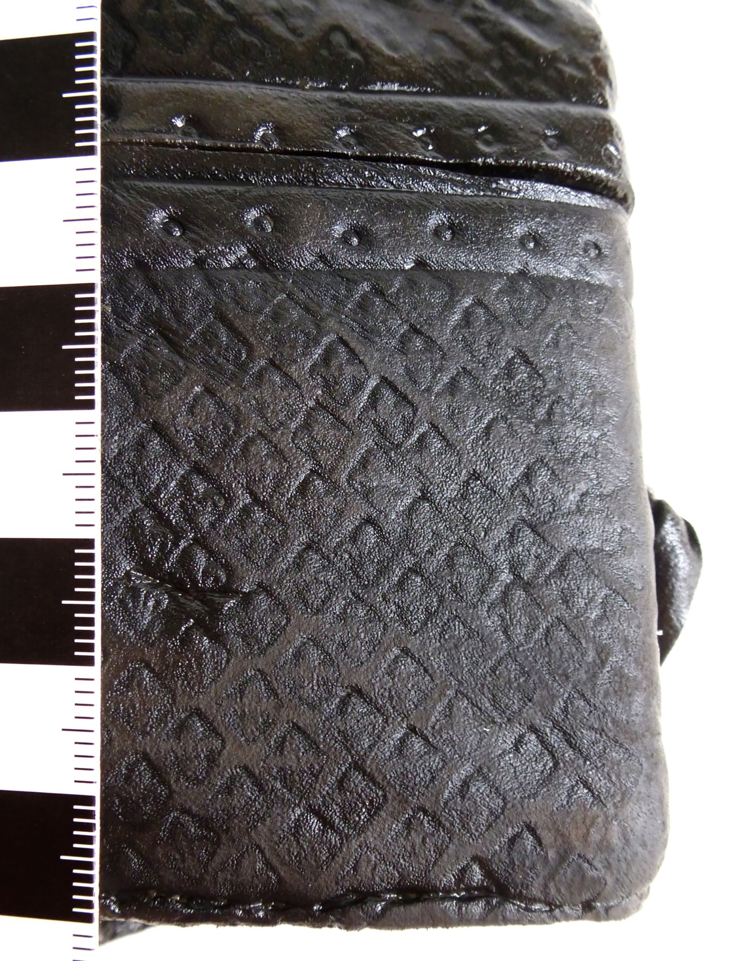 A closeup of a dark leather pouch embossed with a lily motif.