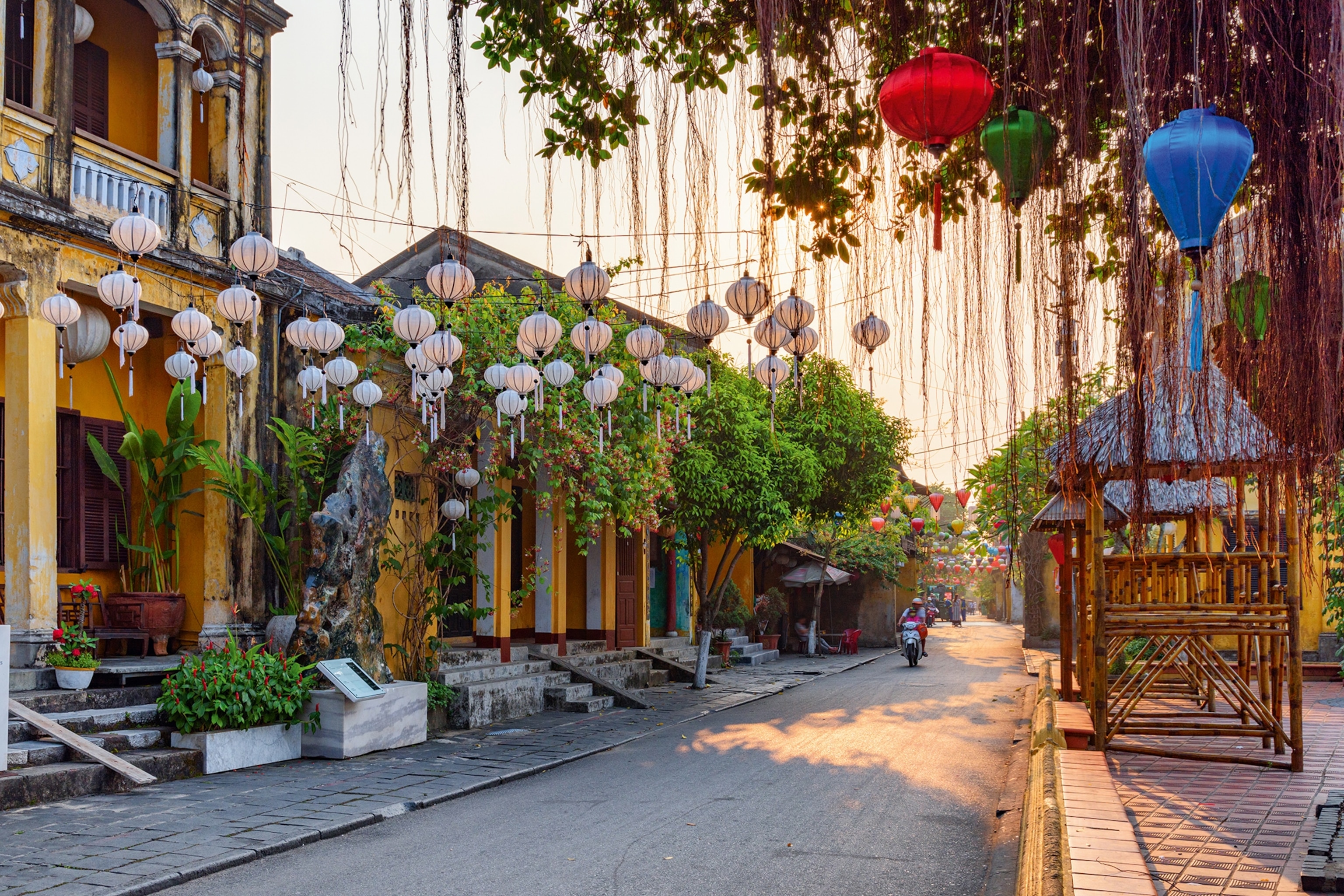 A residential street in Hoi An at sunrise with silk lanterns hung above.