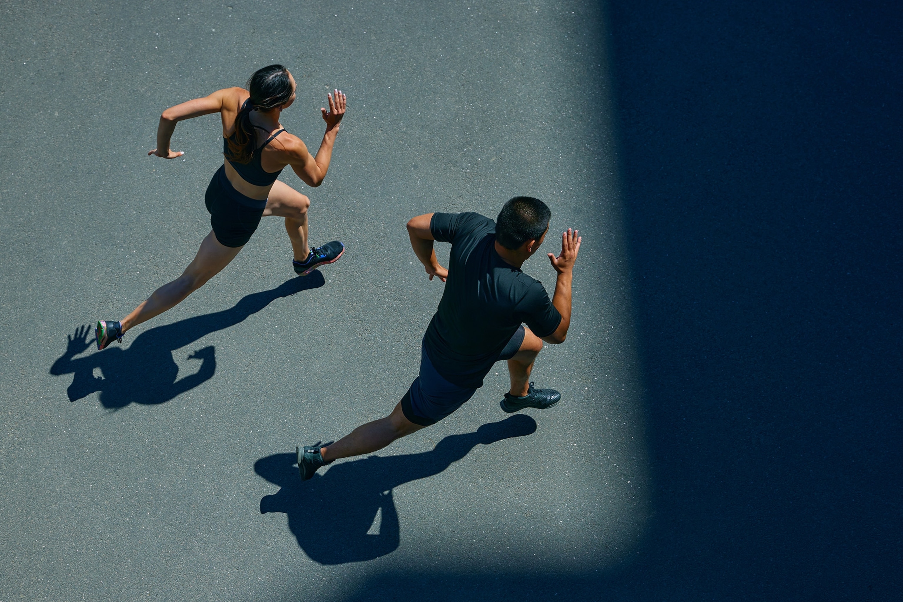 An aerial view of a man and a woman wearing workout clothes running side by side.