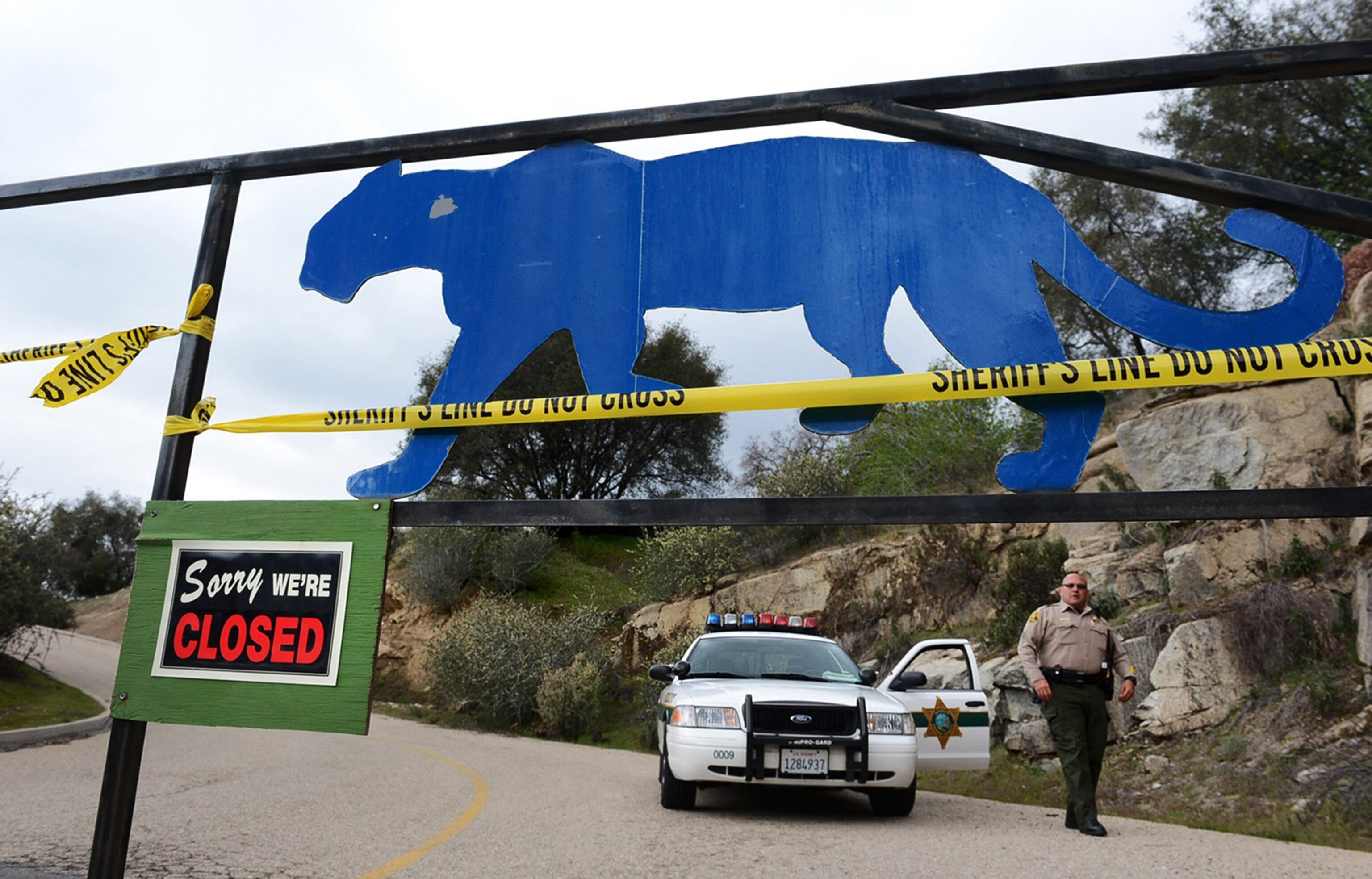 A sheriff's deputy guards the entrance of a cat sanctuary.