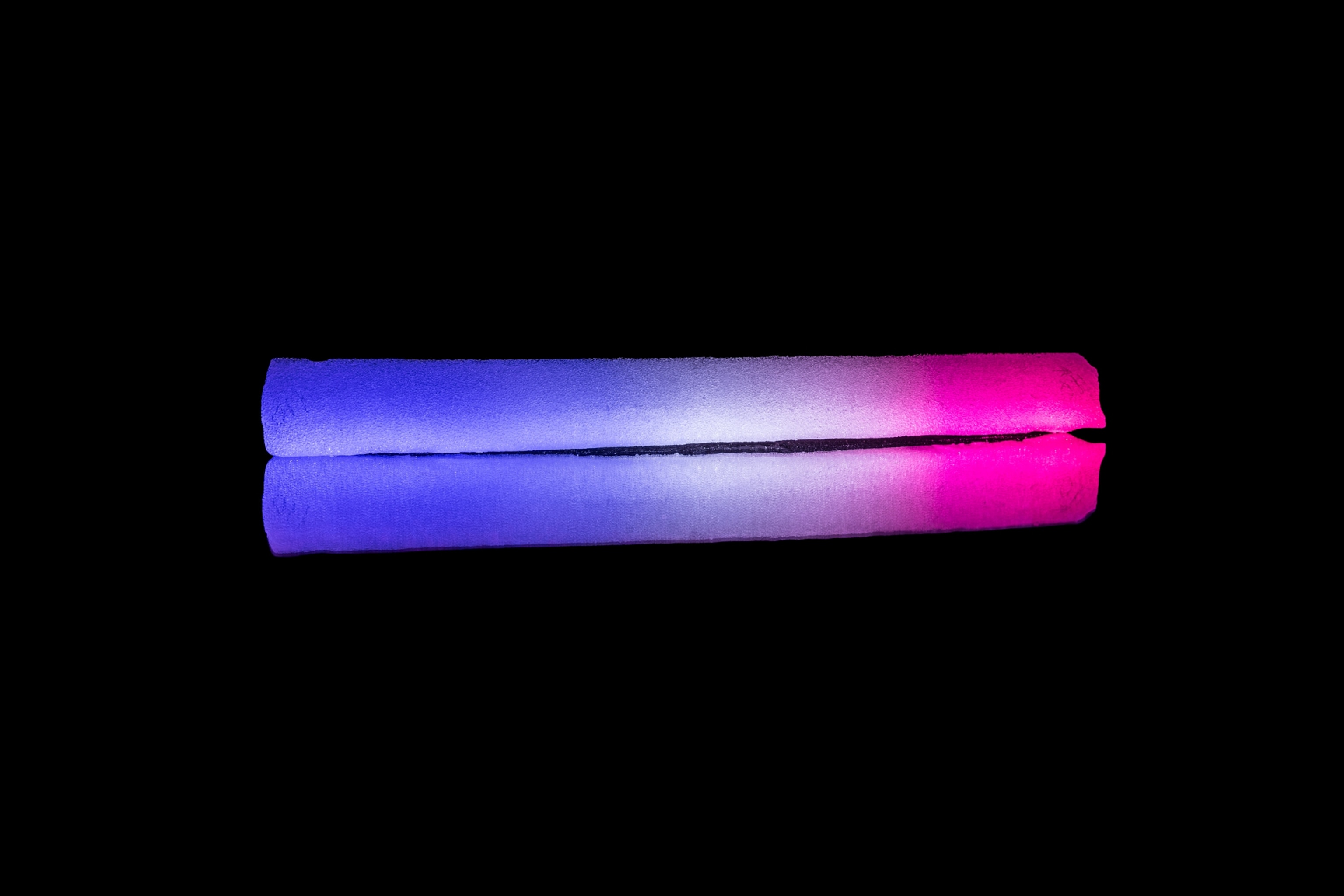 Long cylindrical block of ice in colors gradually changing from blue to hot-pink.