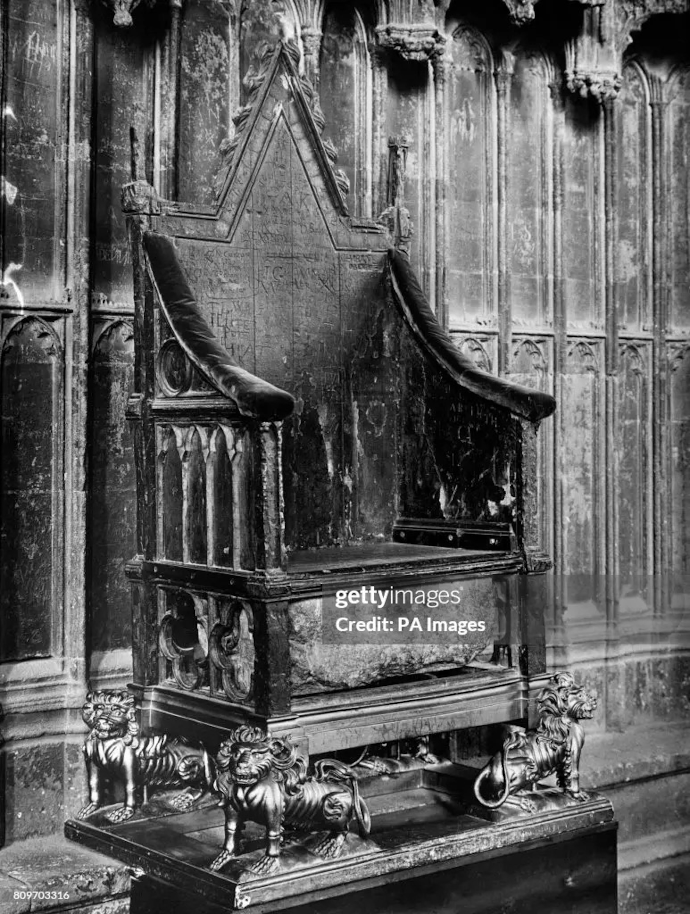 A black and white photo of a throne and a stone sits underneath.