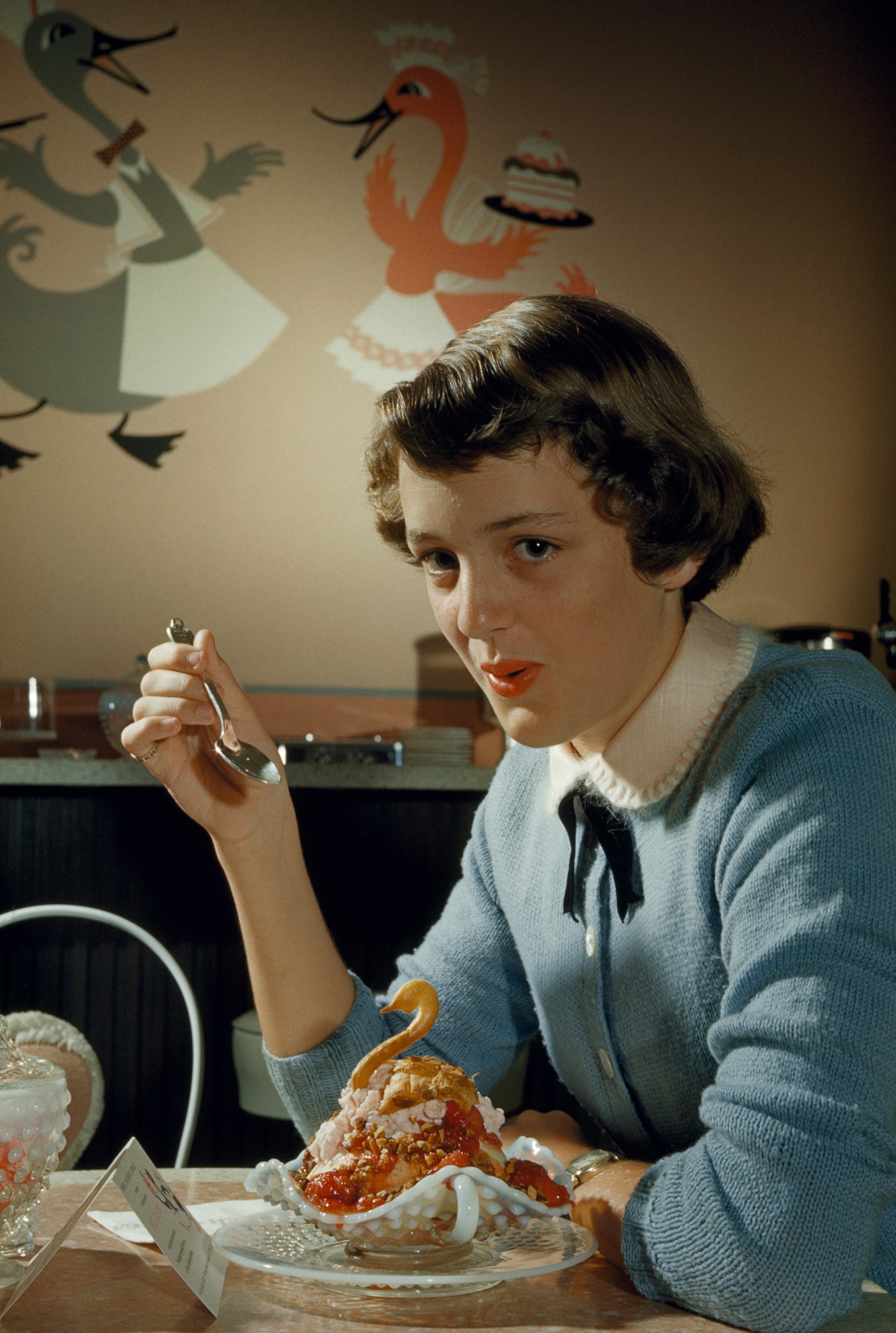 Girl eats special sundae in ice cream parlor.