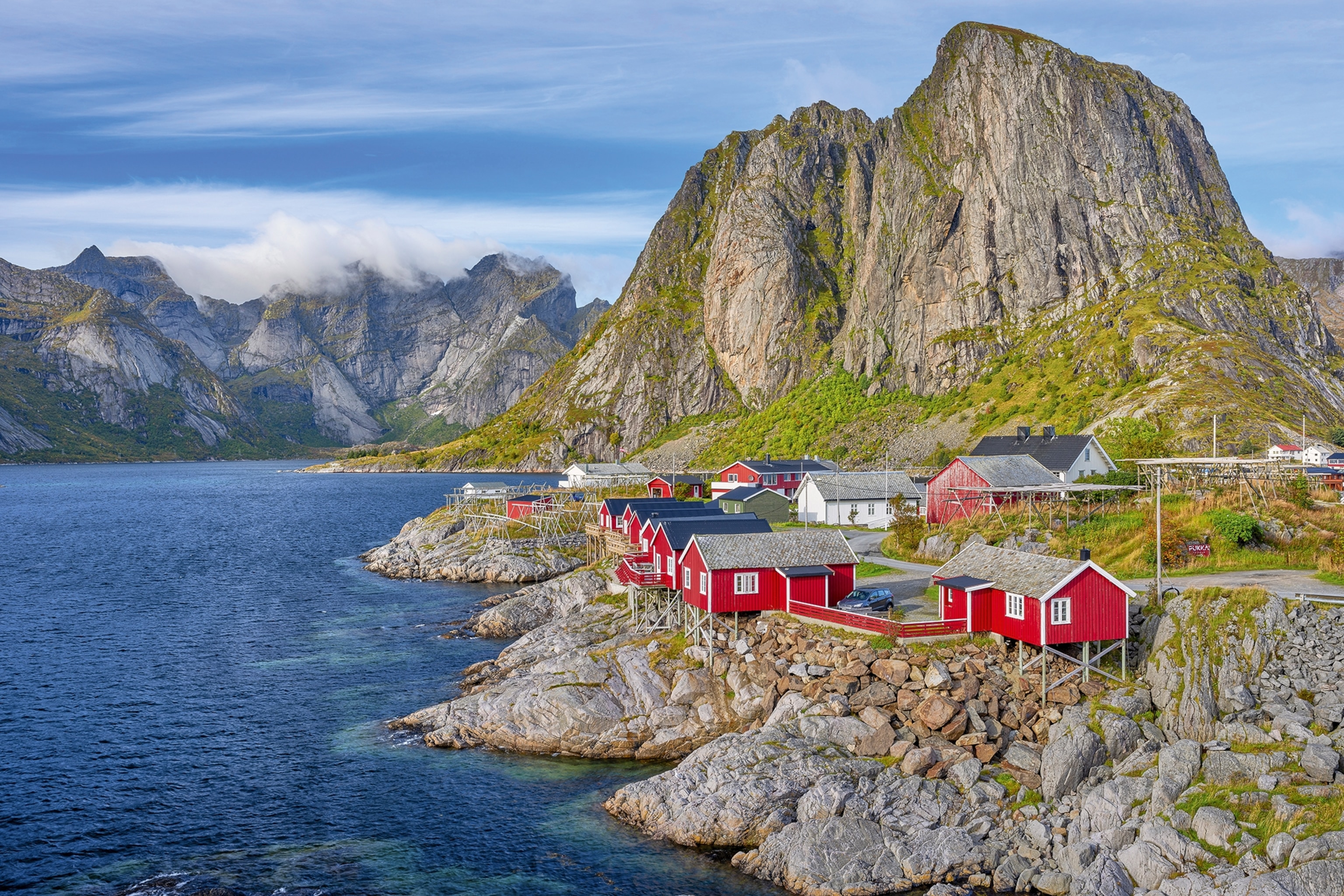 A rugged coastline in Norway with fishing huts built along the edge and the ocean reaching the shore.