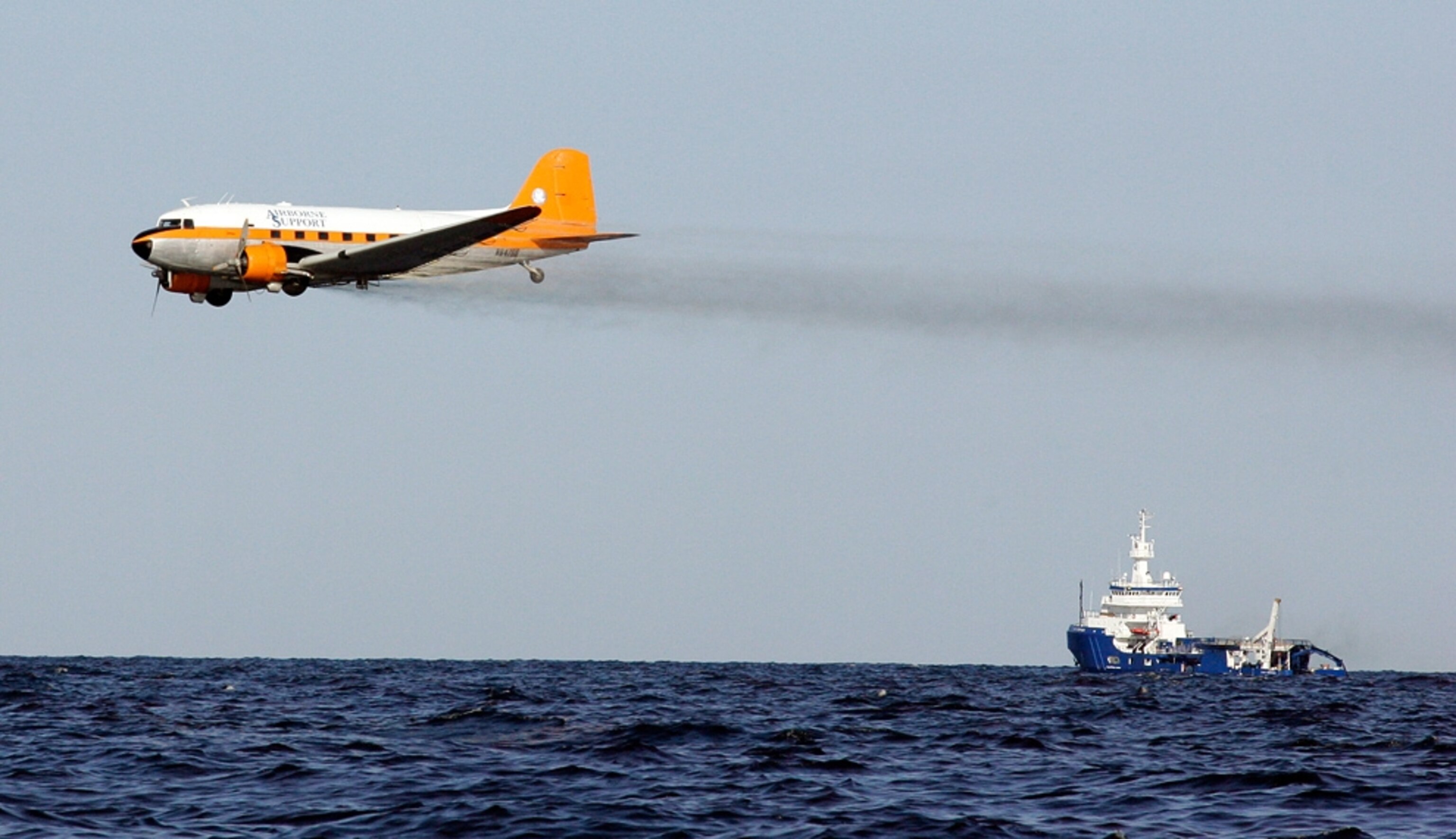 A dispersant plane passes over an oil skimmer as it cleans oil from a leaking pipeline that resulted from last week's explosion and collapse of the Deepwater Horizon oil rig in the Gulf of Mexico near the coast of Louisiana Tuesday, April 27, 2010. (AP Photo/Patrick Semansky)