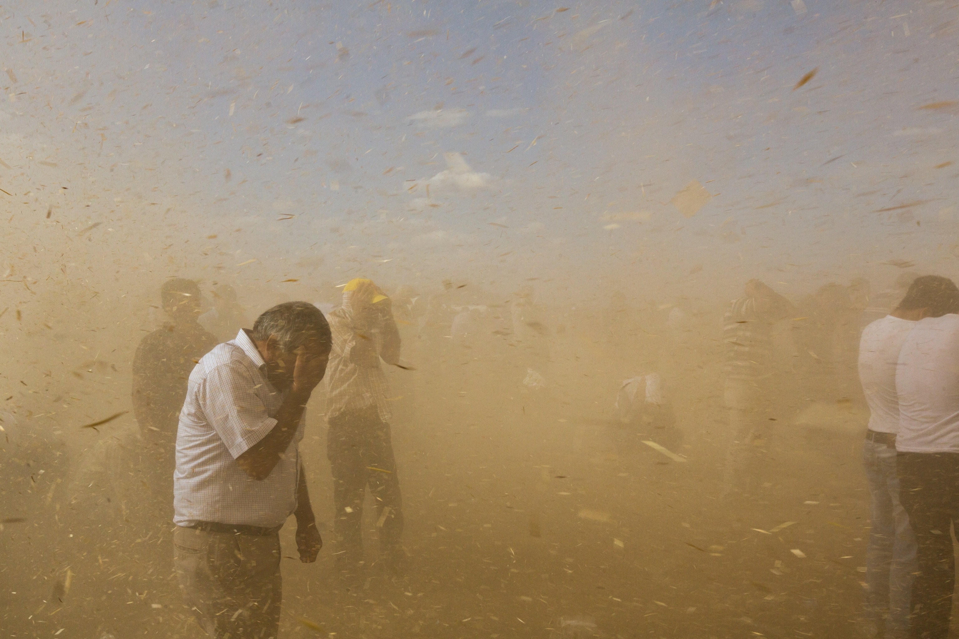refugees covering their faces during a sand storm