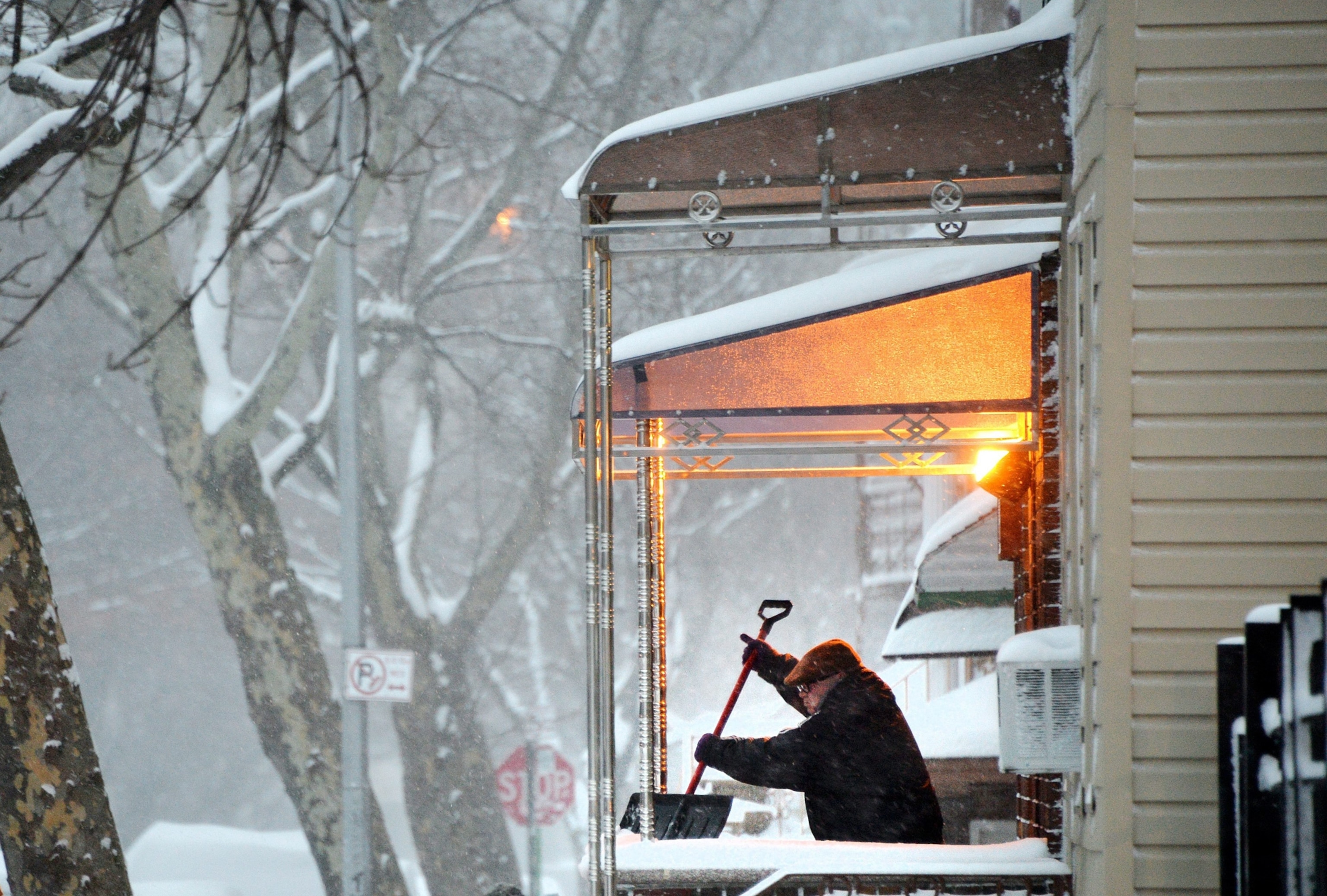 a man shoveling off his porch in Brooklyn, NY, after a snowstorm