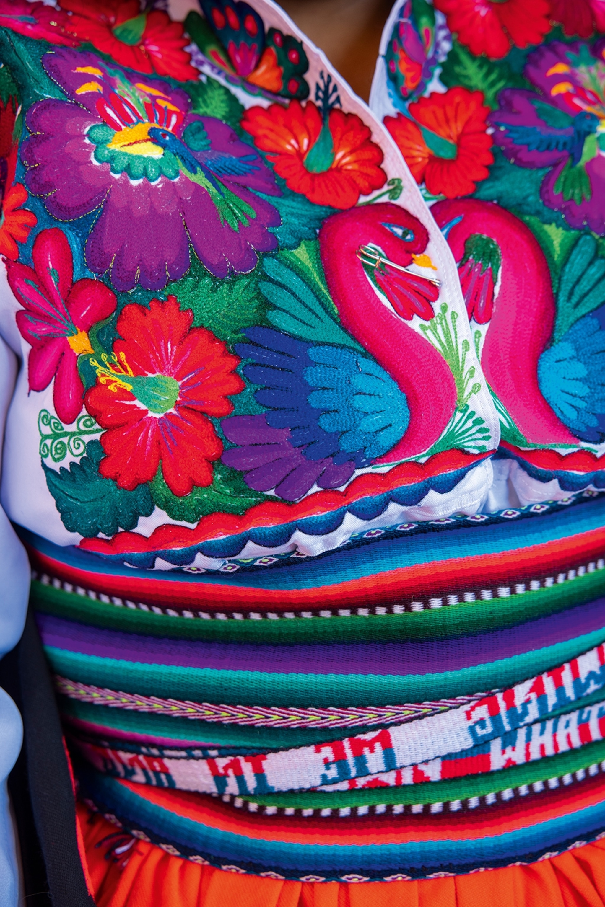 A close-up of a local woman's upper body, focusing on the delicate embroidery of her traditional dress.