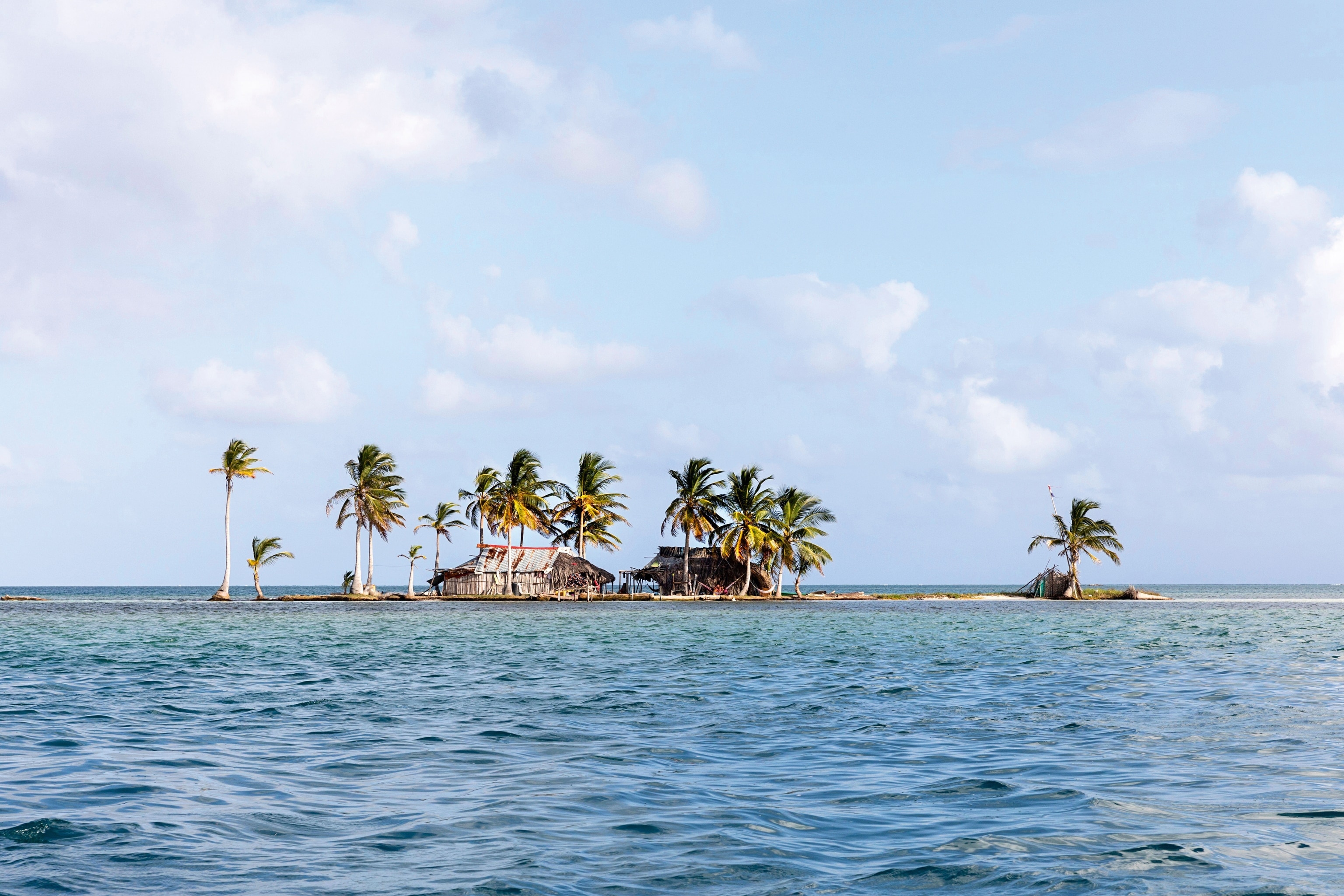 Island with palm trees and wooden houses from a distance
