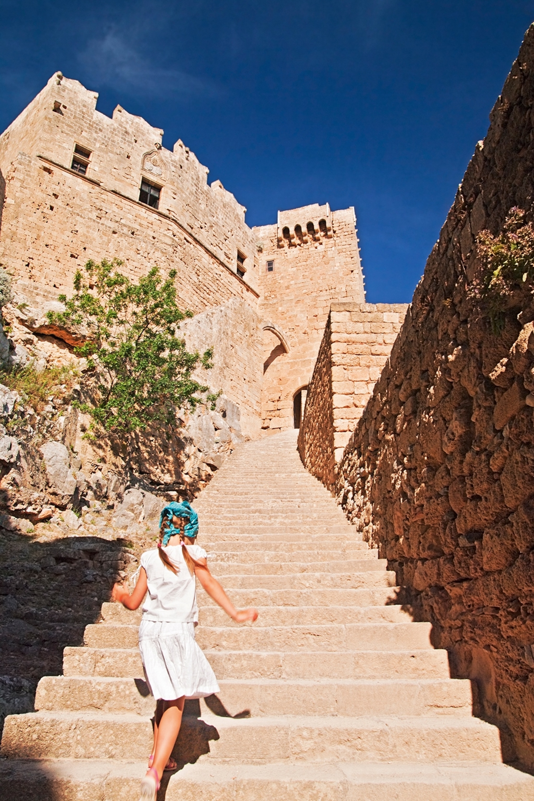 A girl skipping up the stairs to a stone Akropolis.