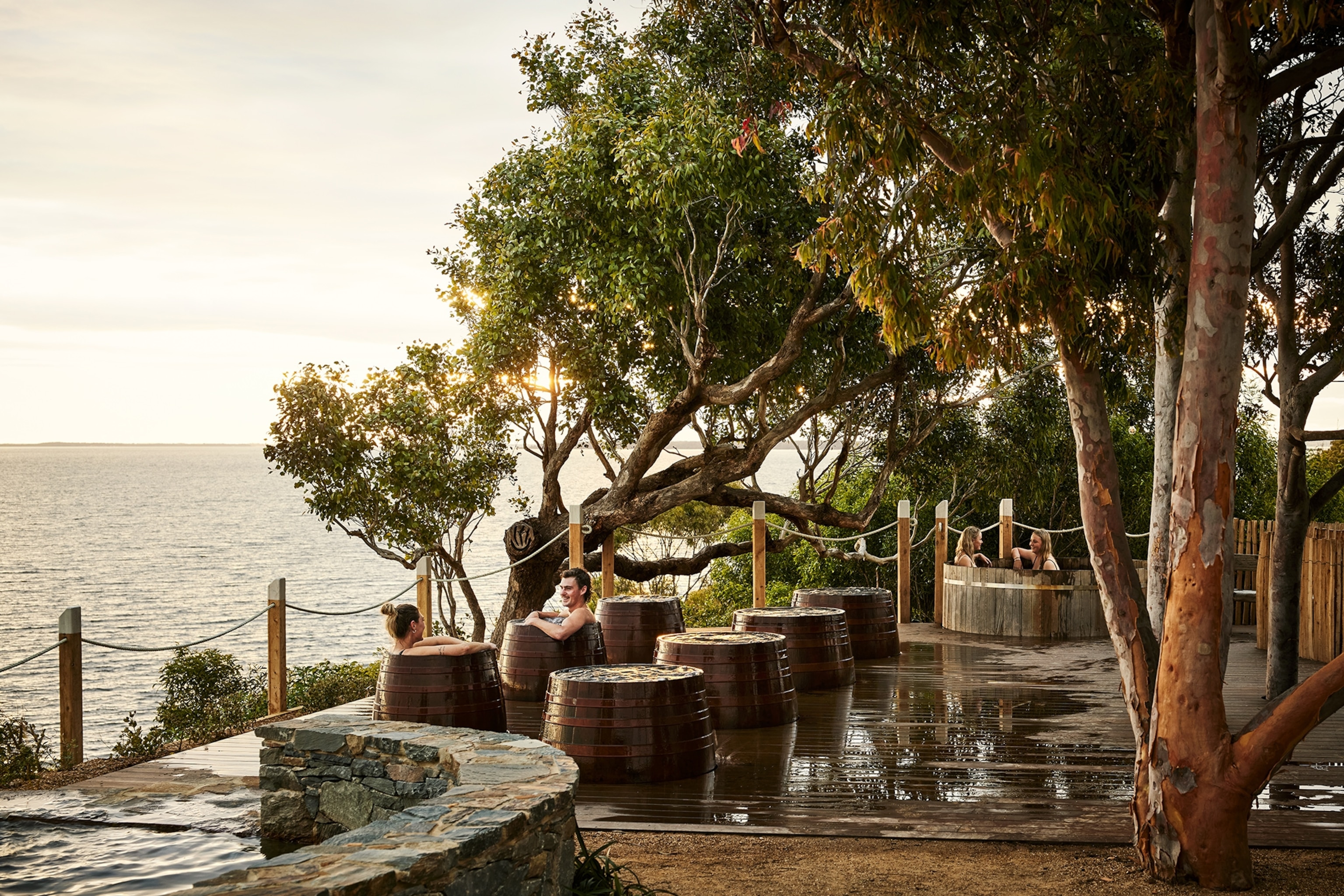 Two people are sitting in a bathing barrel and looking at the water.