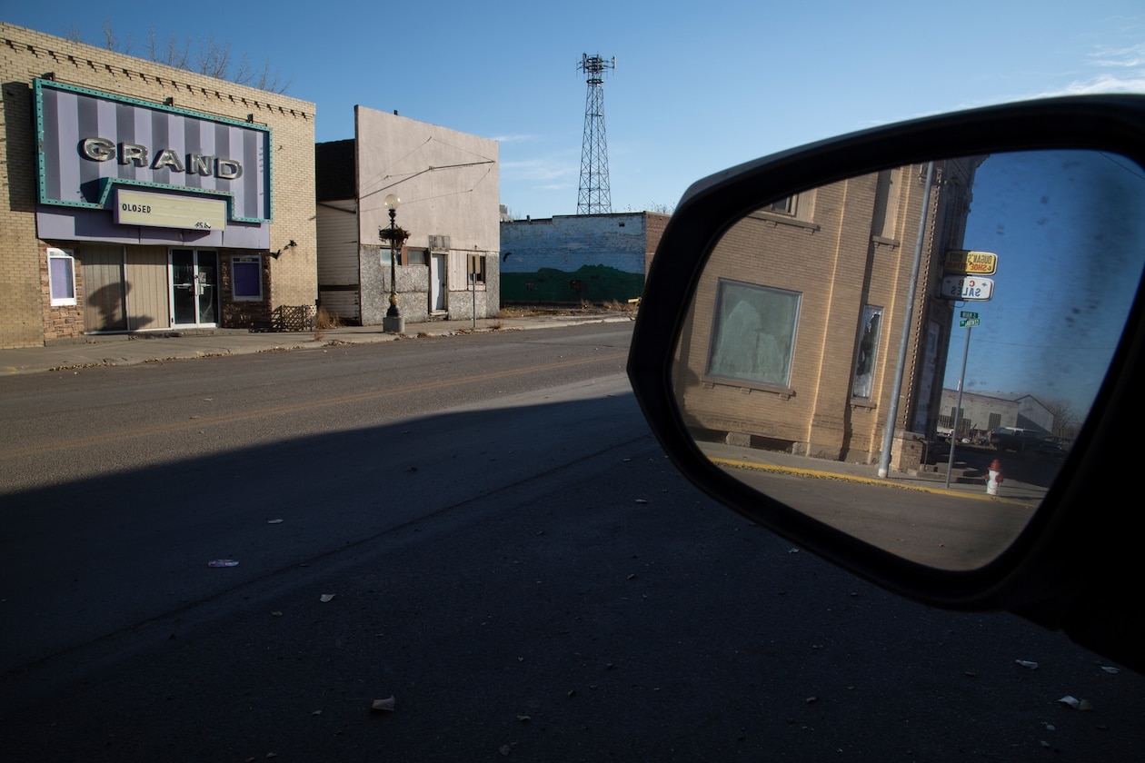 a rearview mirror along a road of empty buildings