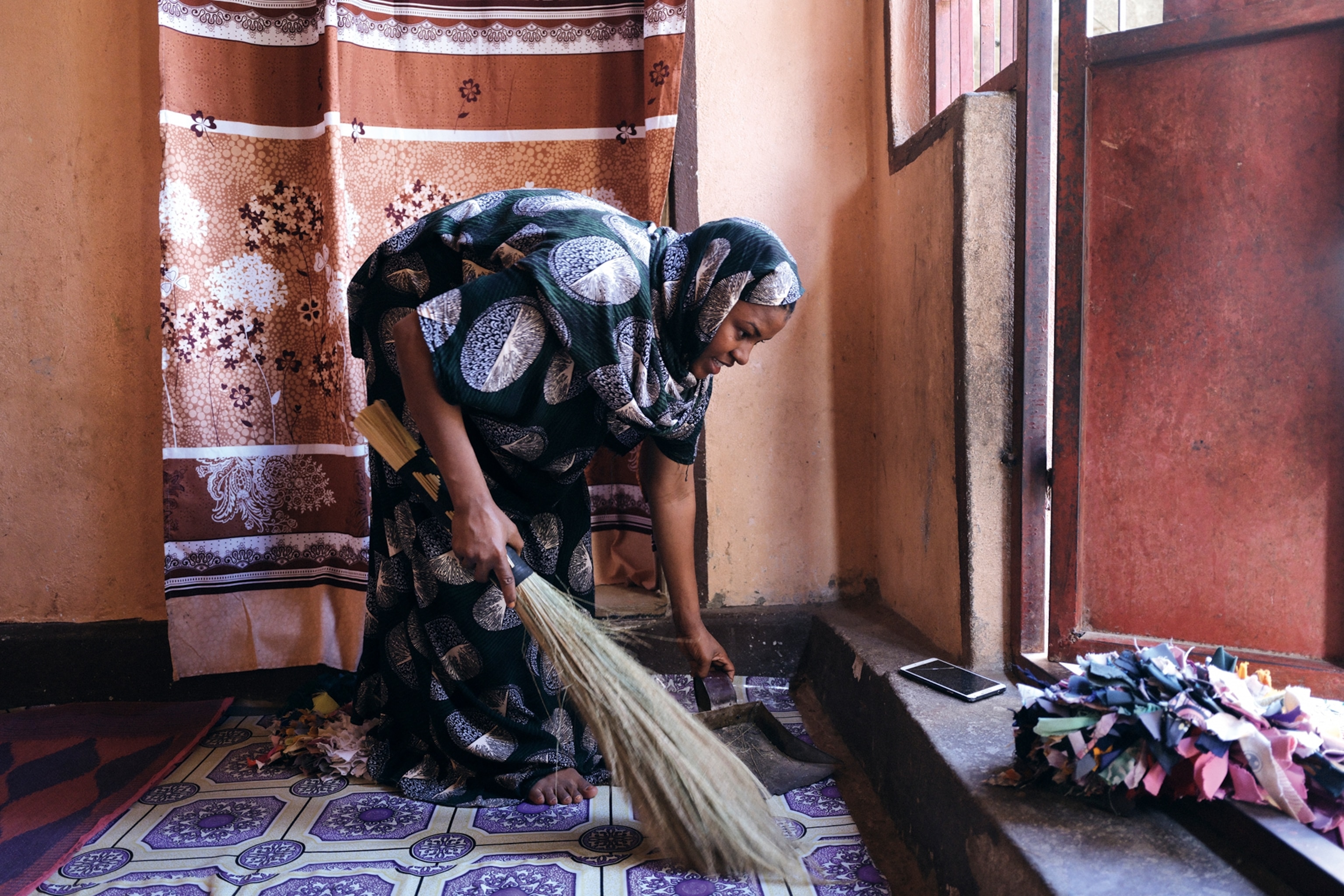 A local woman dusting off the entrance step to her house.