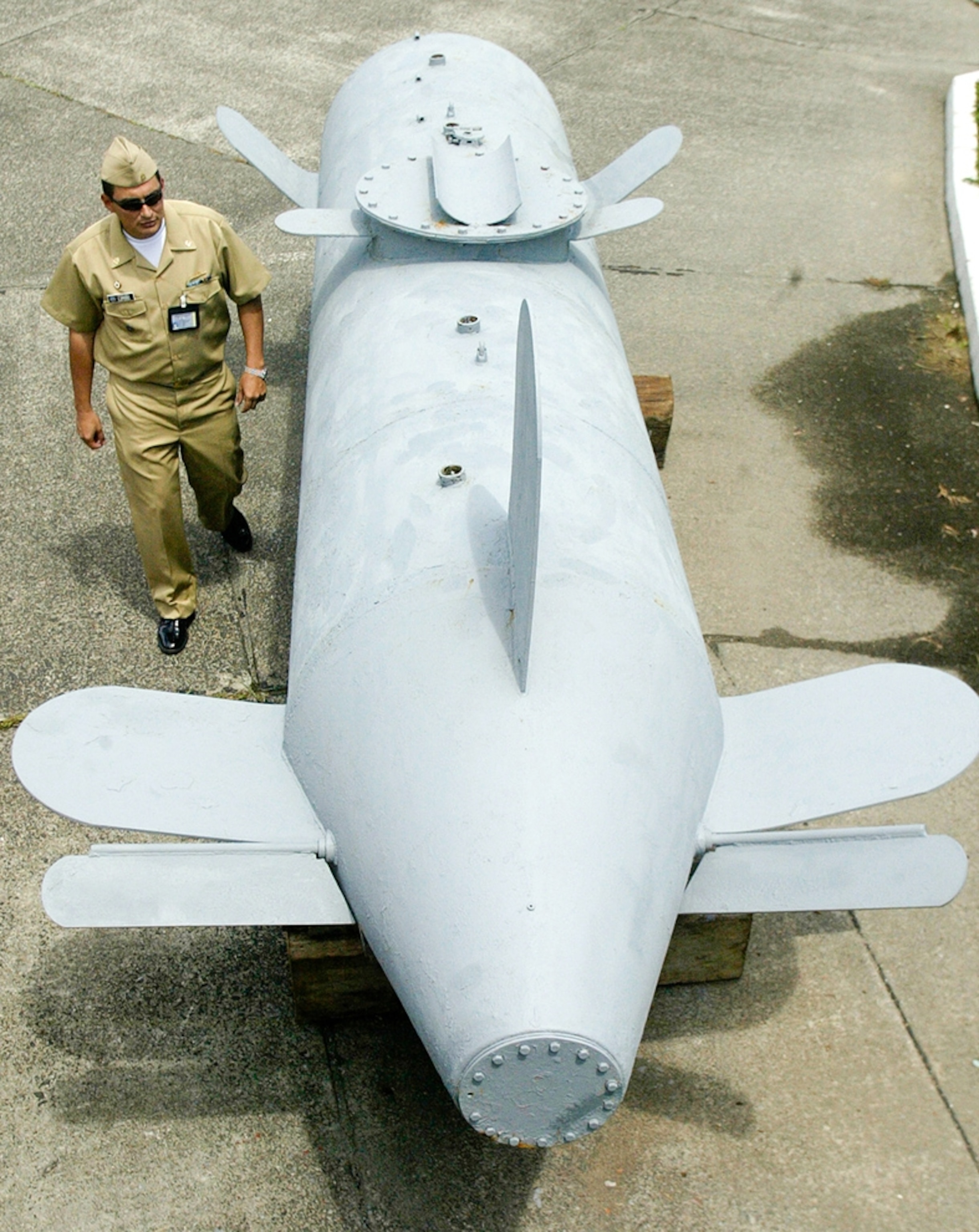 a military official standing next to a torpedo-like, unmanned cocaine "submarine"