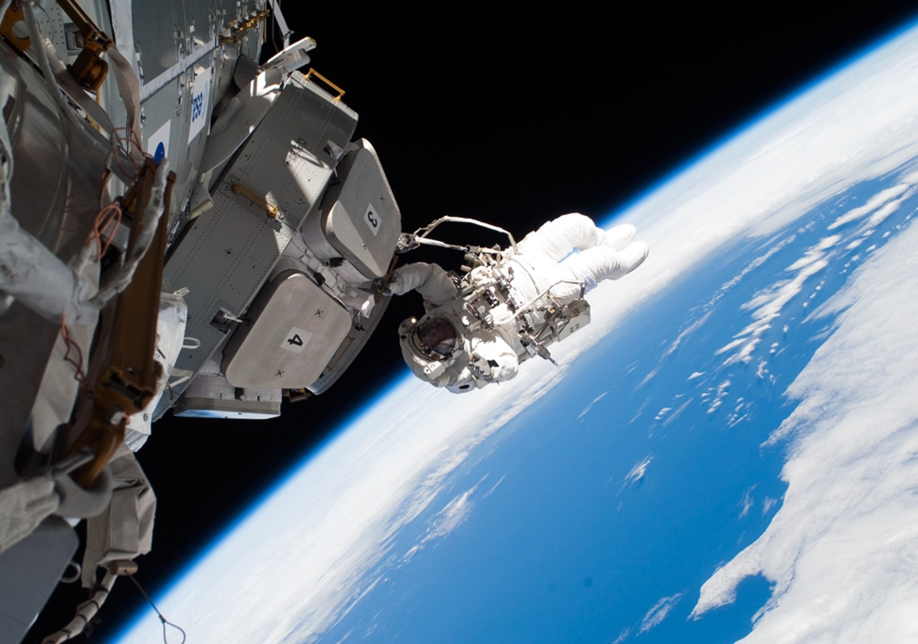 An astronaut works outside the International Space Station with Earth in the background in a NASA picture