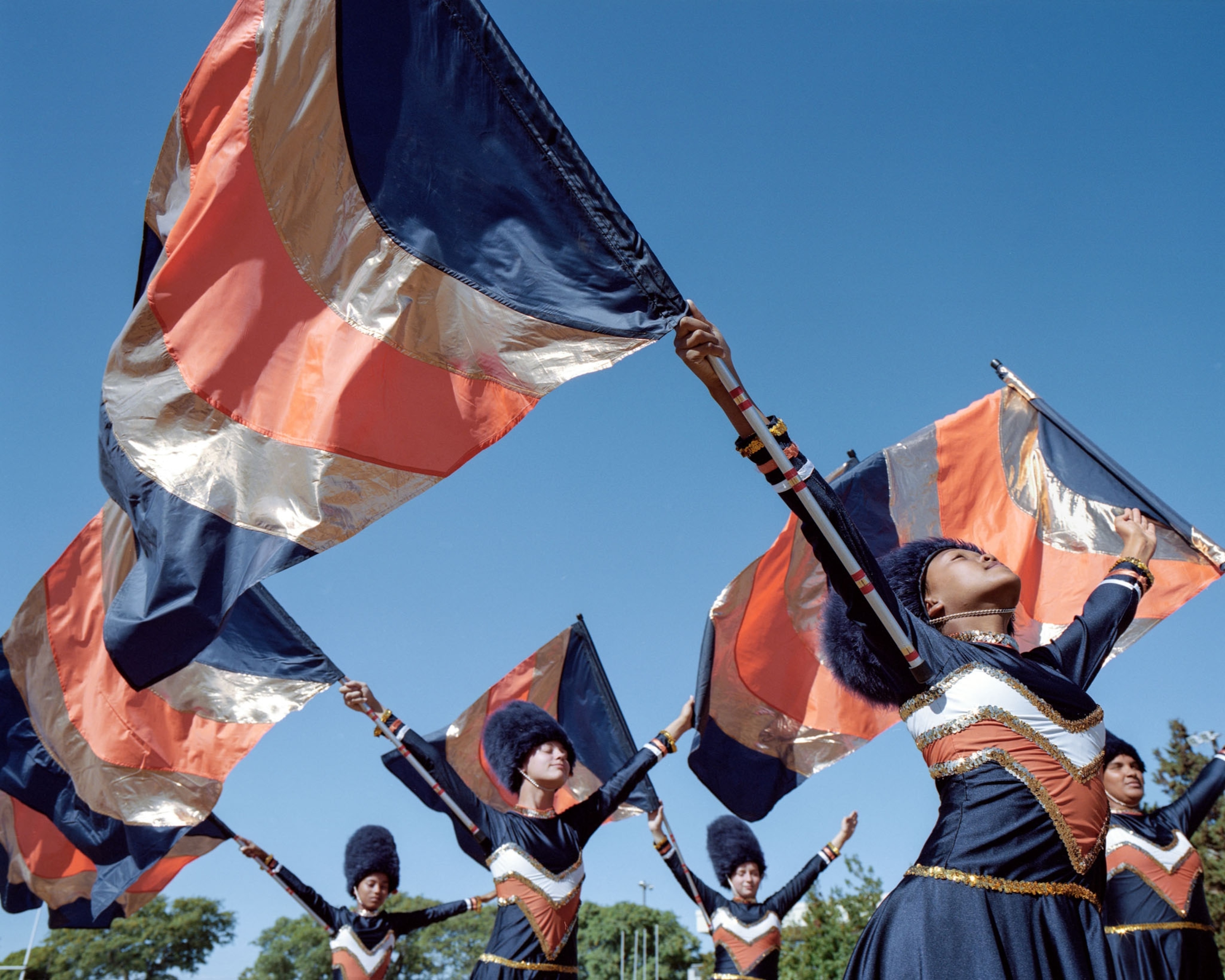 five young women in blue and orange uniforms waving flags